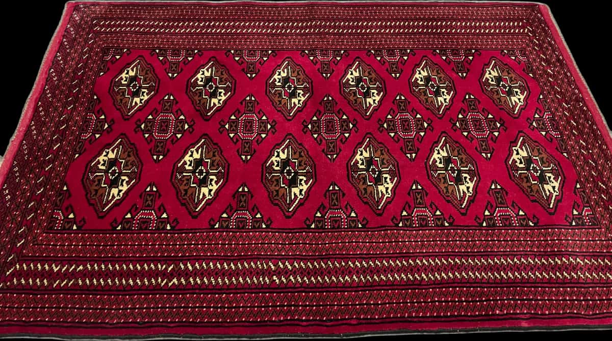 alfombra persa de estilo turcomana en dimensiones 150 centímetros de largo por 103 centímetros de ancho con colores principalmente rojo — Perspectiva