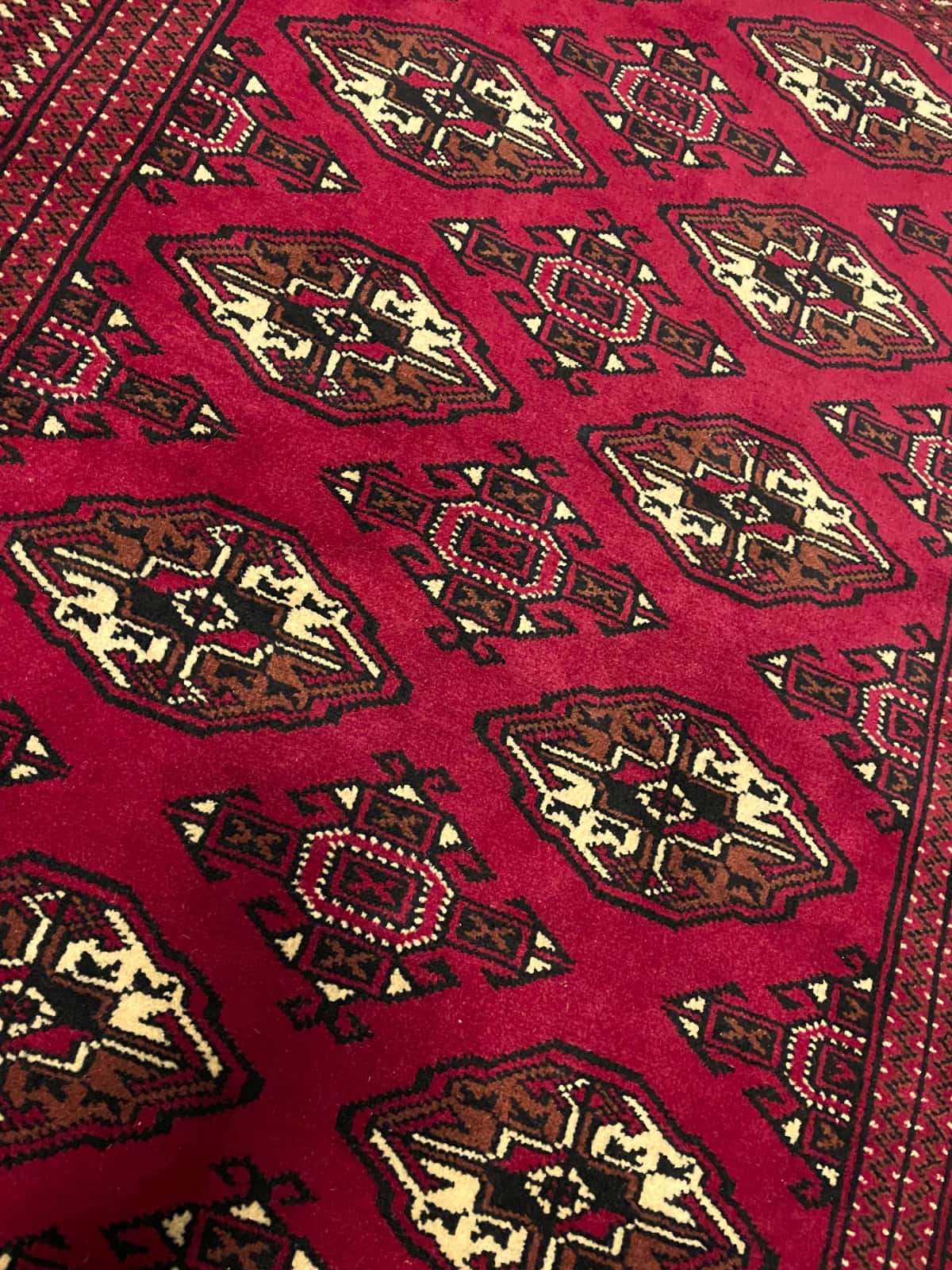 alfombra persa de estilo turcomana en dimensiones 150 centímetros de largo por 103 centímetros de ancho con colores principalmente rojo — Primer plano de la textura