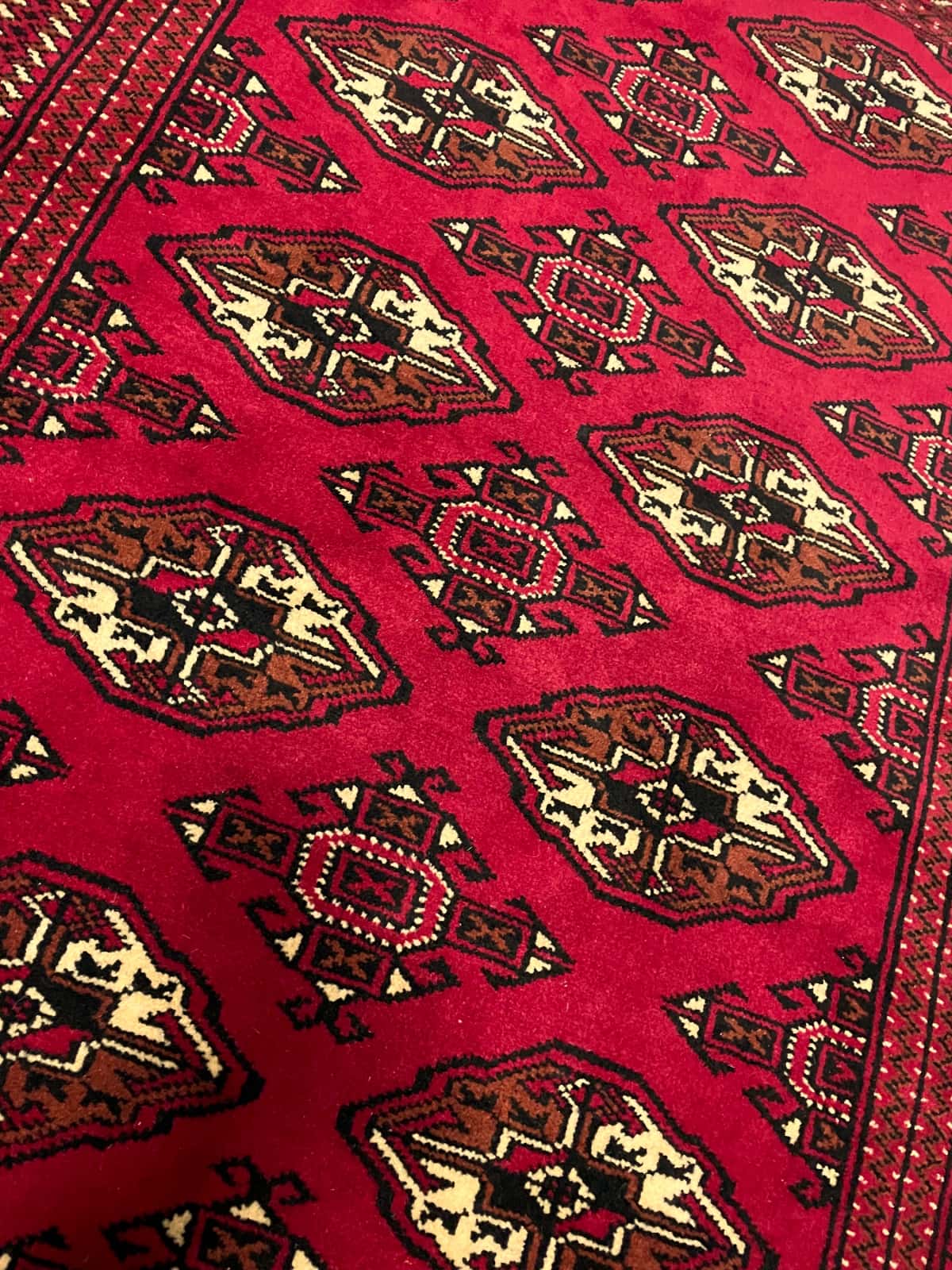 persischer Teppich im turkmenischer Stil in den Maßen 150 Zentimeter Länge mal 103 Zentimeter Breite mit überwiegend rot Farben — Nahaufnahme der Textur