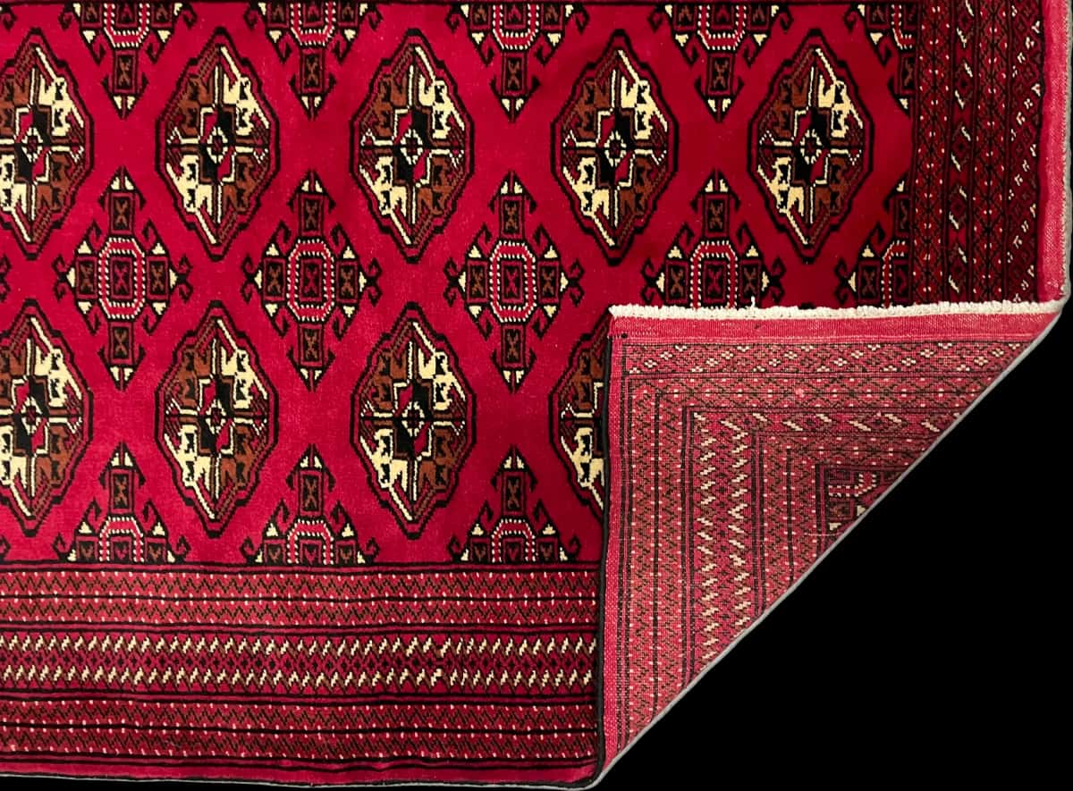 persischer Teppich im turkmenischer Stil in den Maßen 150 Zentimeter Länge mal 103 Zentimeter Breite mit überwiegend rot Farben — Gefaltet