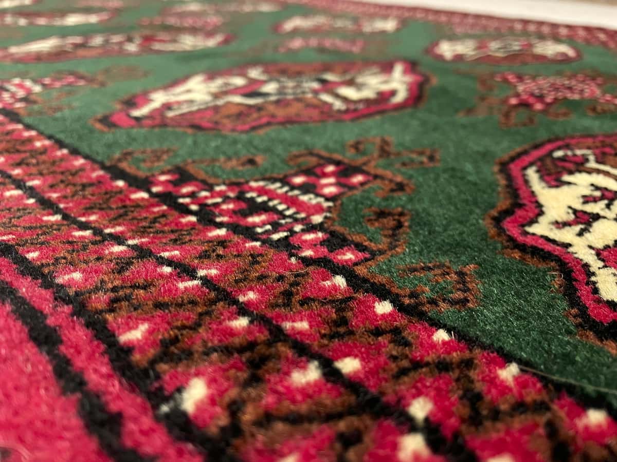 alfombra persa de estilo turcomana en dimensiones 145 centímetros de largo por 97 centímetros de ancho con colores principalmente verde — Primer plano de la textura