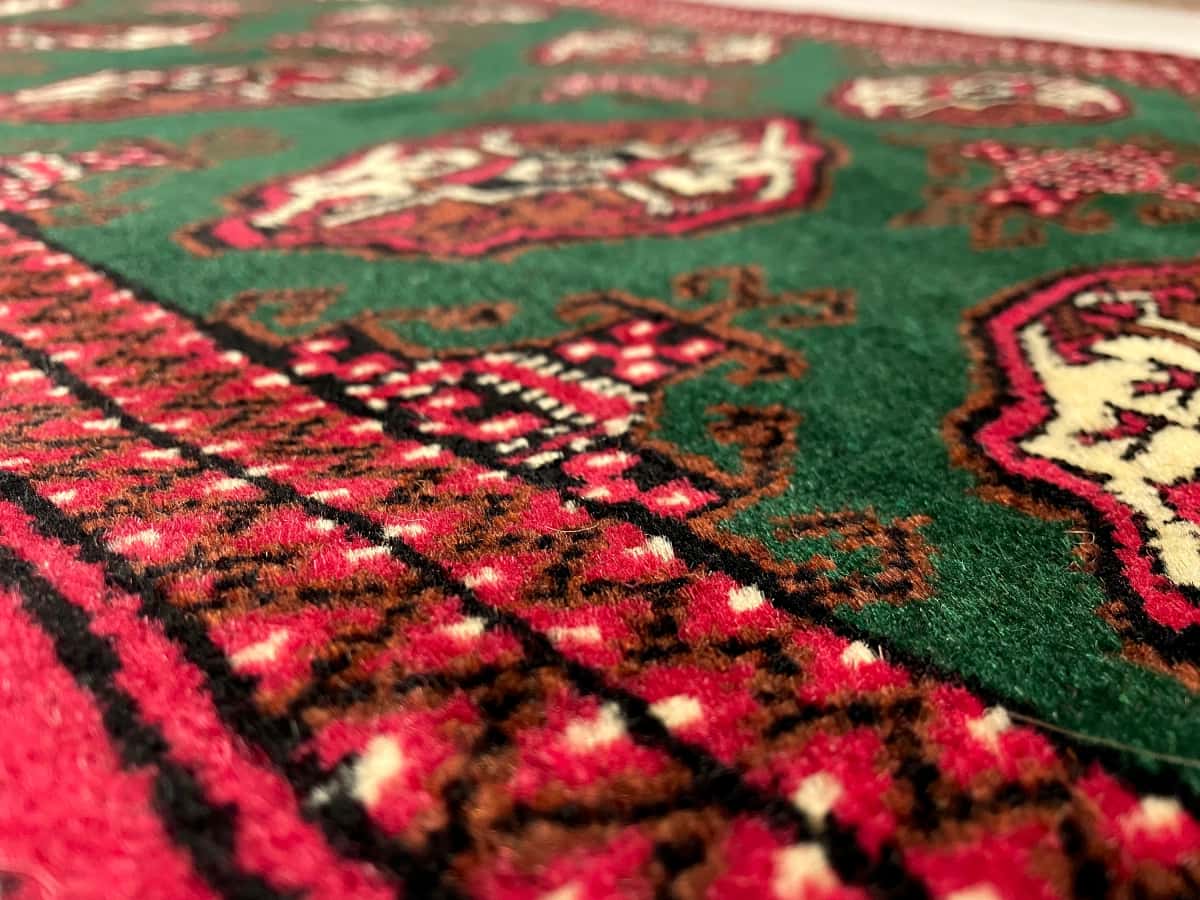 Persian rug of Turkoman style in dimensions 145 centimeters length by 97 centimeters width with mainly green colors — Texture close-up