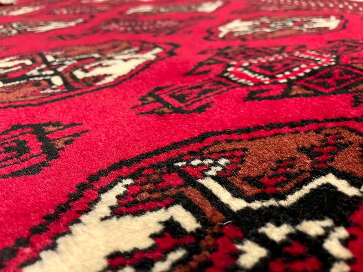 persischer Teppich im turkmenischer Stil in den Maßen 149 Zentimeter Länge mal 98 Zentimeter Breite mit überwiegend rot Farben — Nahaufnahme der Textur
