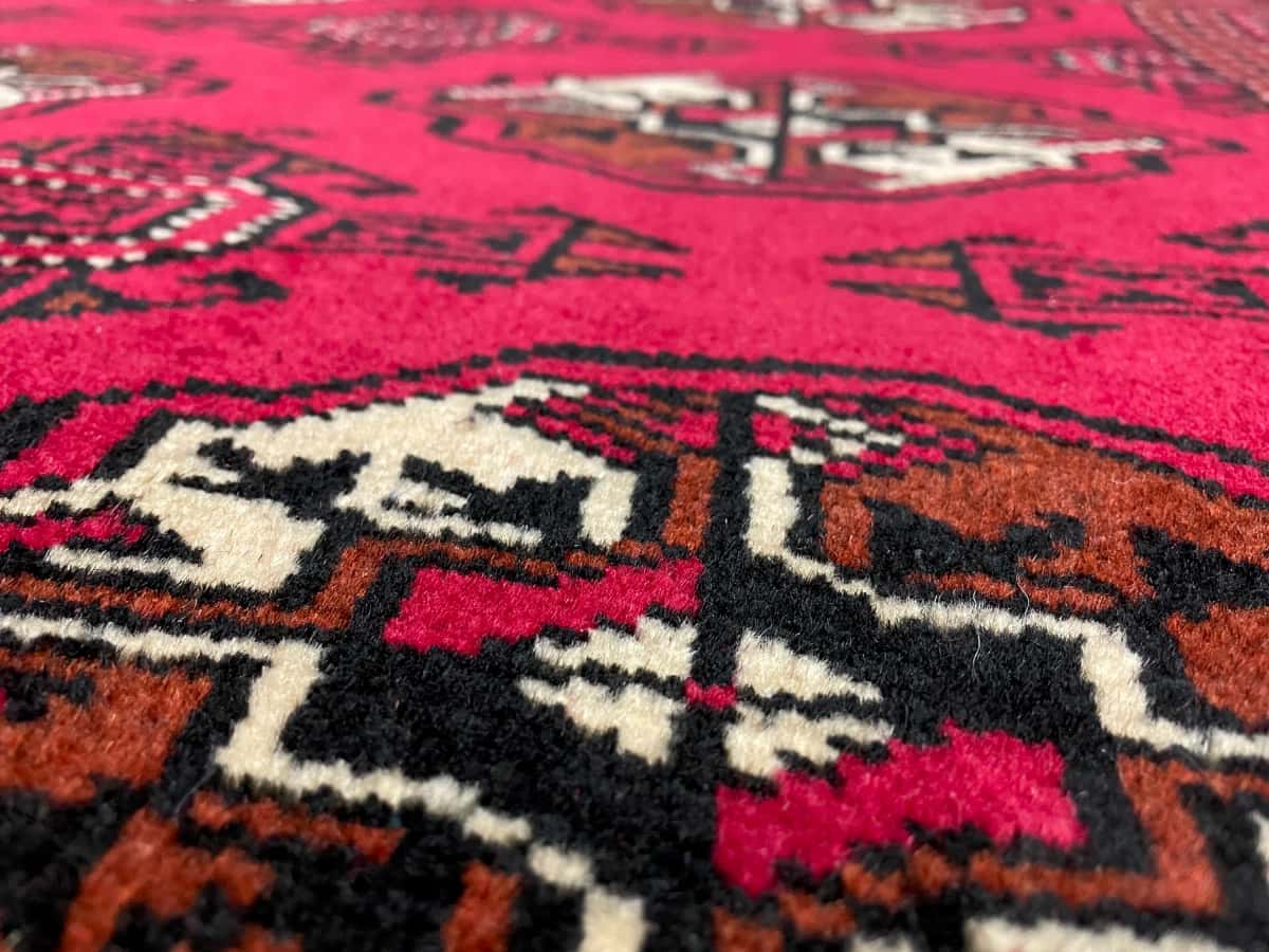 persischer Teppich im turkmenischer Stil in den Maßen 147 Zentimeter Länge mal 98 Zentimeter Breite mit überwiegend rot Farben — Nahaufnahme der Textur