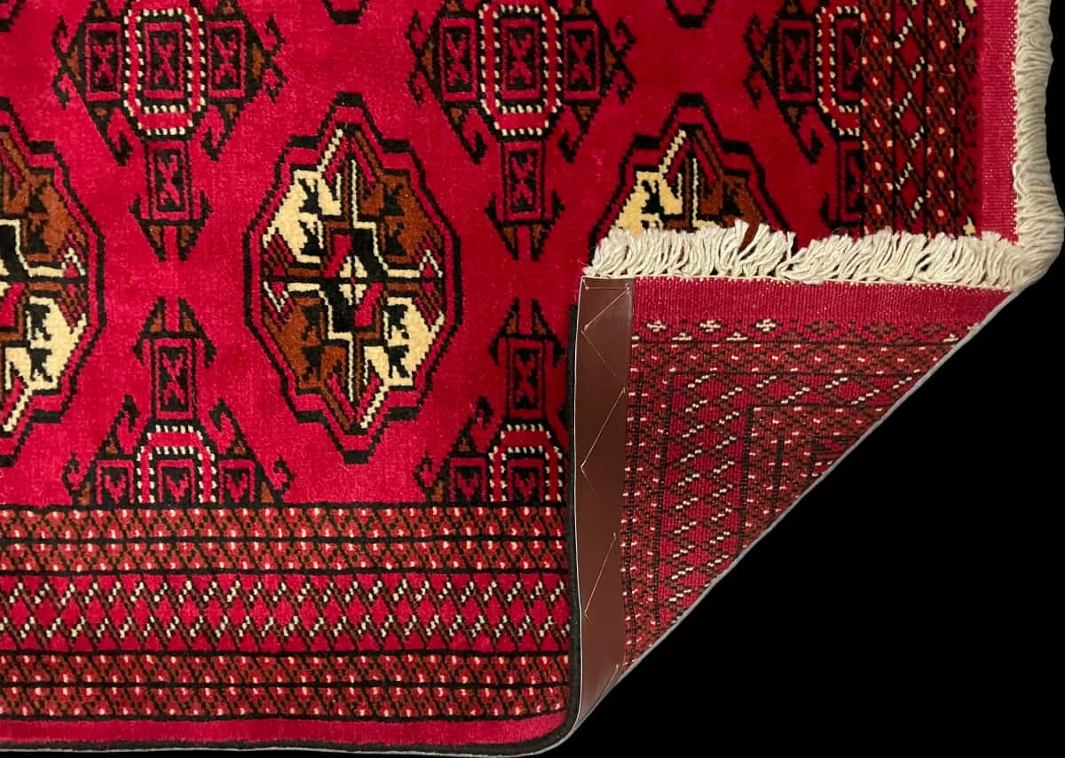 persischer Teppich im turkmenischer Stil in den Maßen 147 Zentimeter Länge mal 98 Zentimeter Breite mit überwiegend rot Farben — Gefaltet