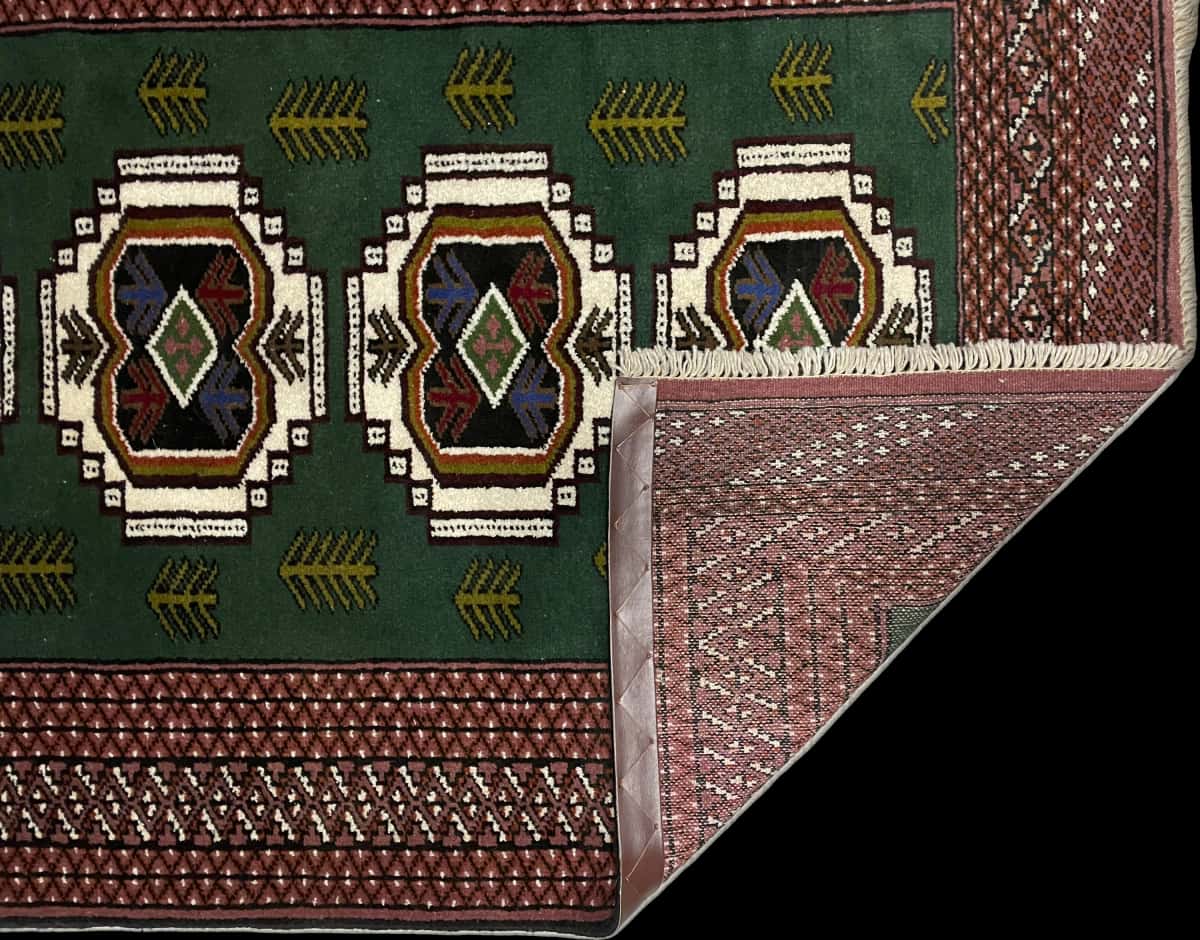 alfombra persa de estilo turcomana en dimensiones 145 centímetros de largo por 100 centímetros de ancho con colores principalmente verde — Plegada