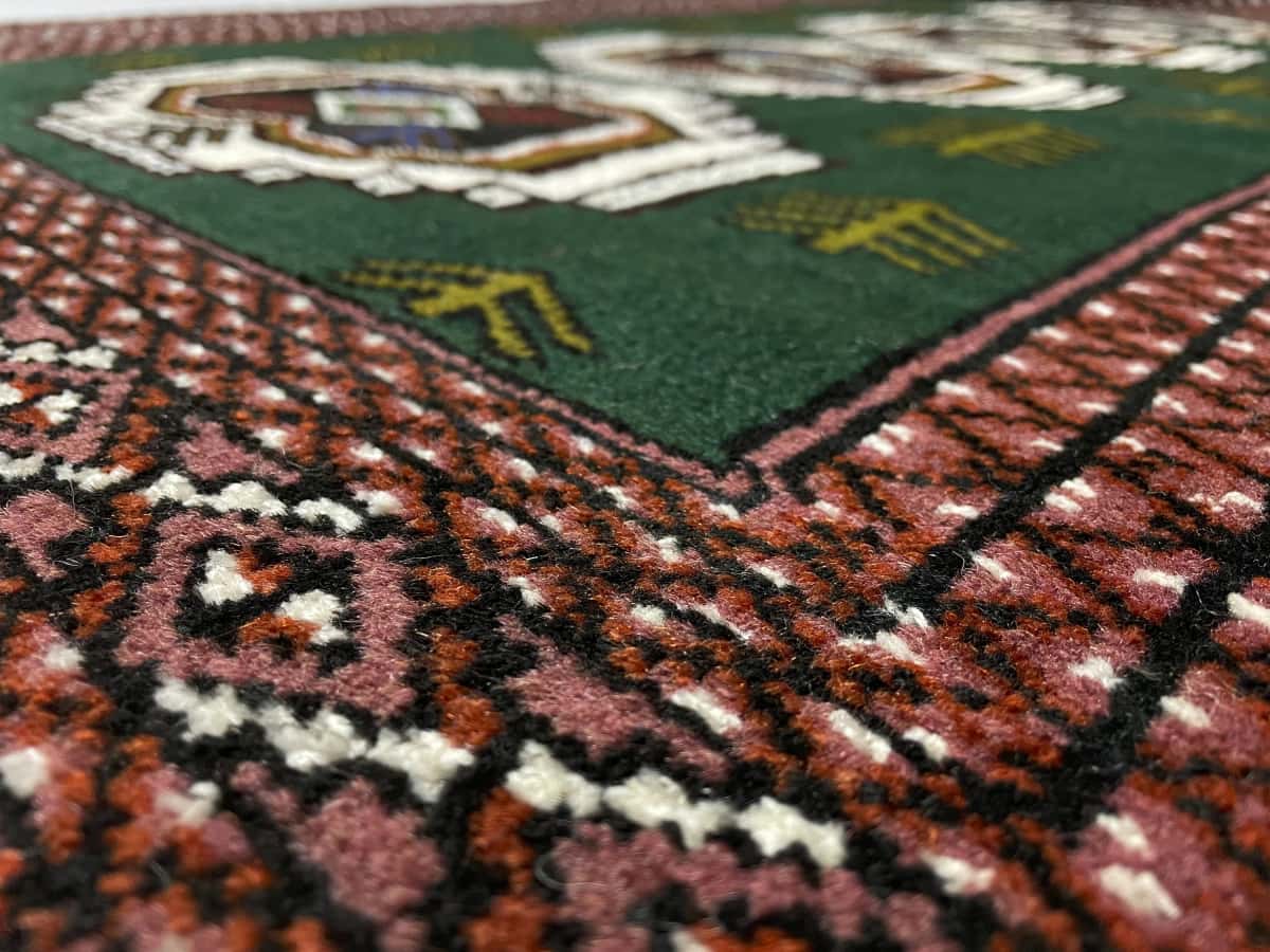 alfombra persa de estilo turcomana en dimensiones 145 centímetros de largo por 100 centímetros de ancho con colores principalmente verde — Primer plano de la textura