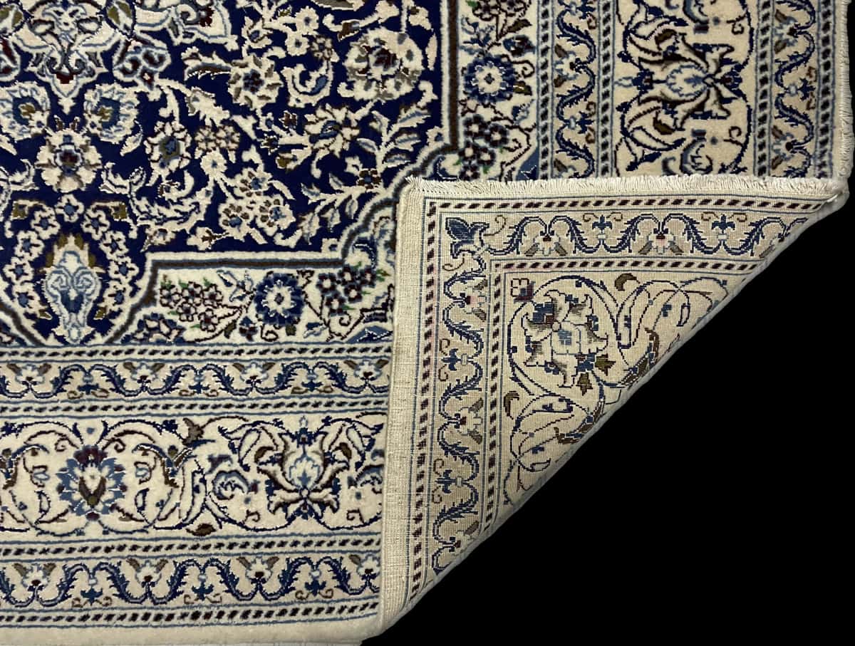 alfombra persa de estilo Nain en dimensiones 202 centímetros de largo por 195 centímetros de ancho con colores principalmente azul — Plegada