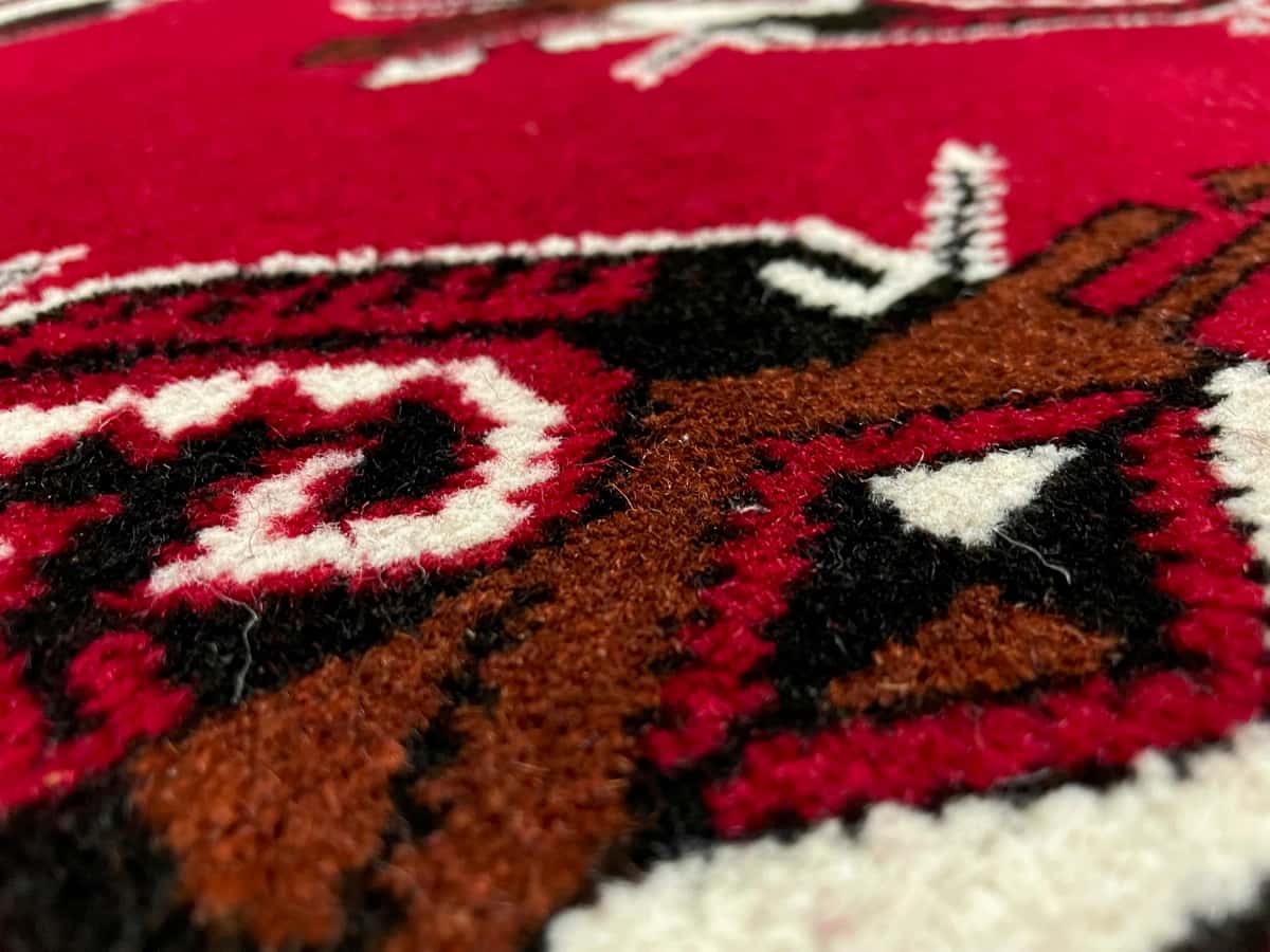 persischer Teppich im turkmenischer Stil in den Maßen 150 Zentimeter Länge mal 98 Zentimeter Breite mit überwiegend rot Farben — Nahaufnahme der Textur