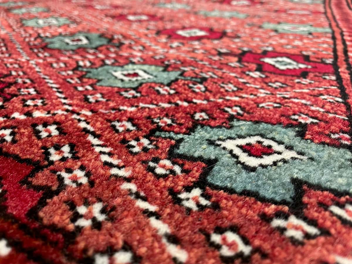 persischer Teppich im turkmenischer Stil in den Maßen 150 Zentimeter Länge mal 102 Zentimeter Breite mit überwiegend braun und rot Farben — Nahaufnahme der Textur