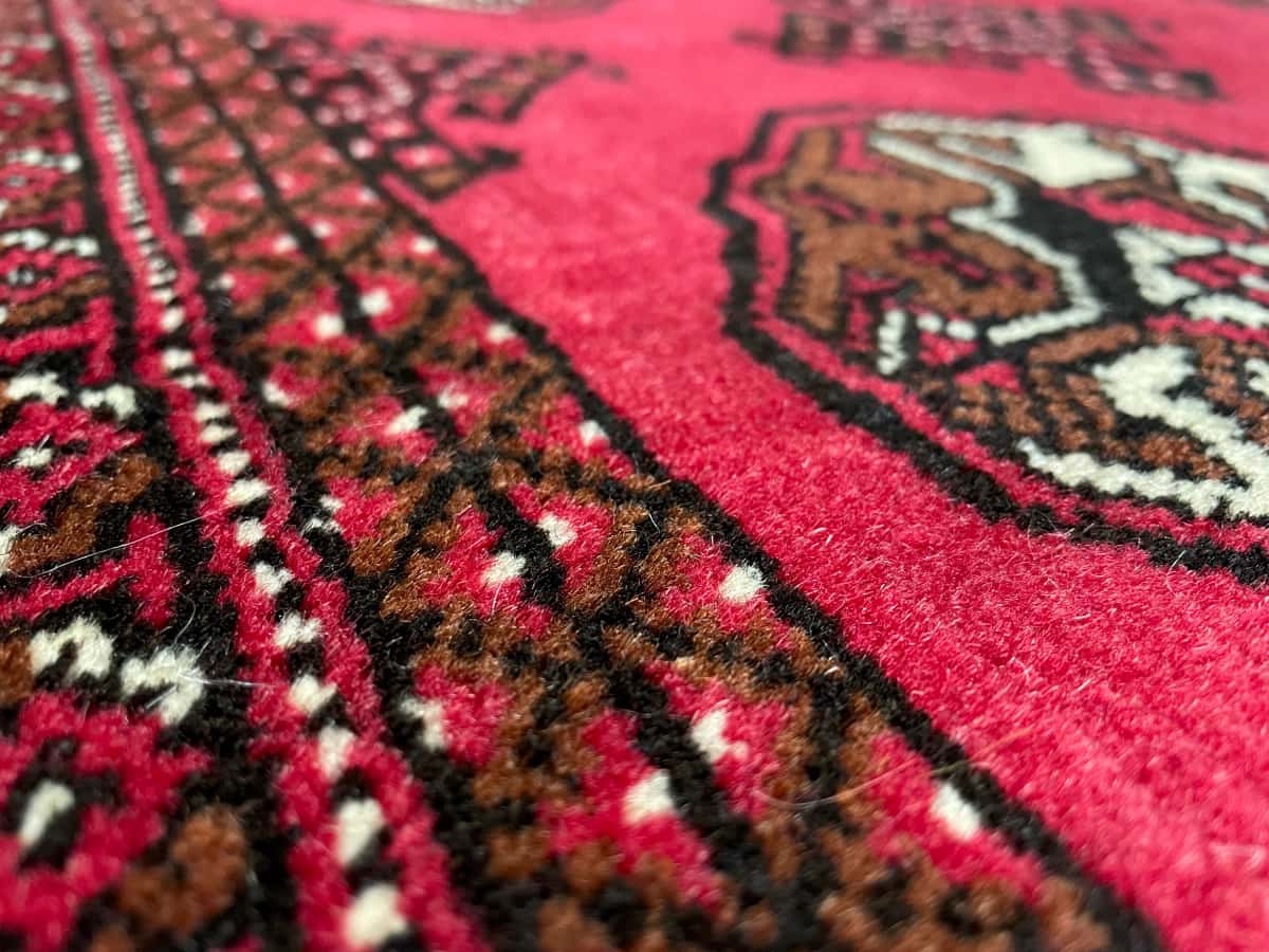 persischer Teppich im turkmenischer Stil in den Maßen 150 Zentimeter Länge mal 104 Zentimeter Breite mit überwiegend rot Farben — Nahaufnahme der Textur