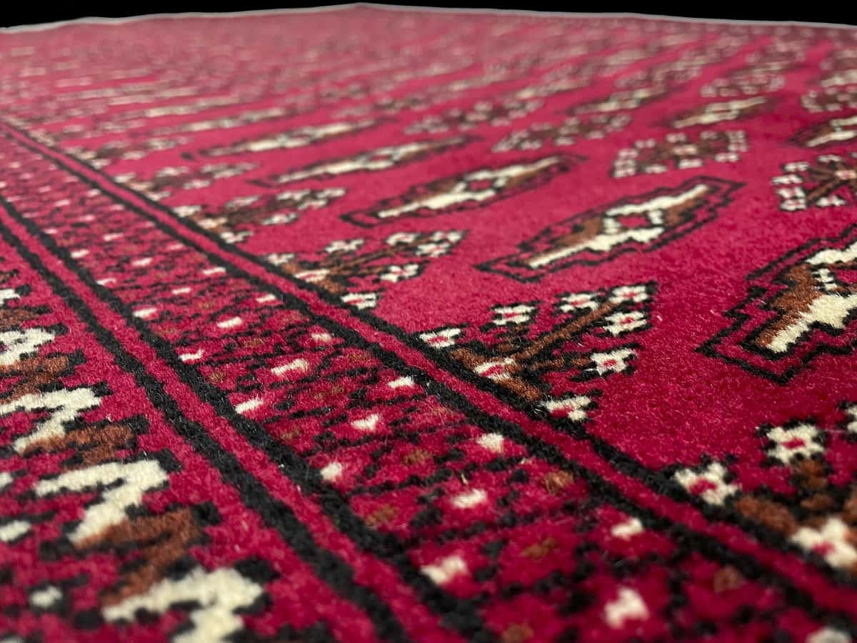alfombra persa de estilo turcomana en dimensiones 148 centímetros de largo por 101 centímetros de ancho con colores principalmente rojo — Primer plano de la textura