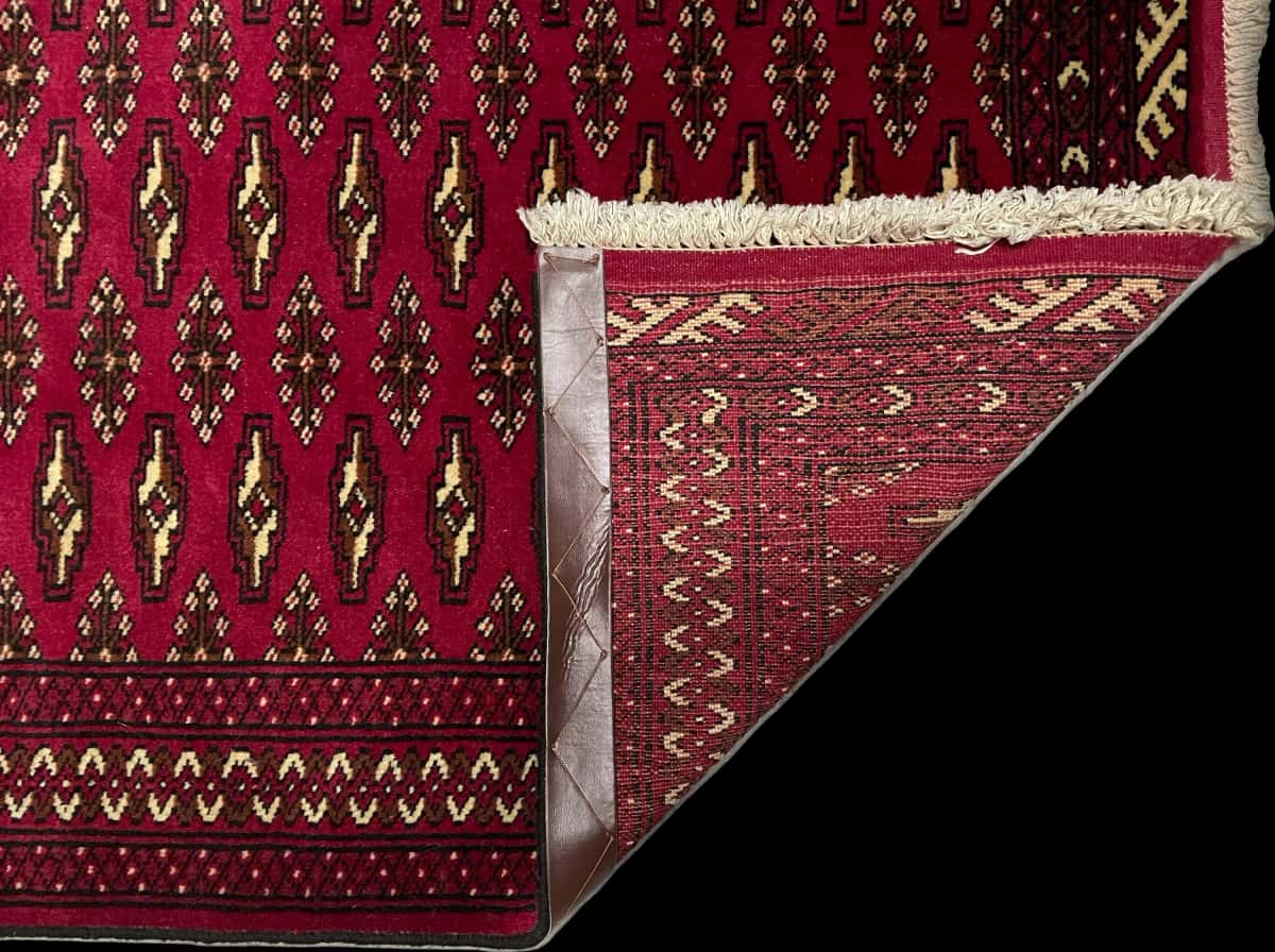 alfombra persa de estilo turcomana en dimensiones 148 centímetros de largo por 101 centímetros de ancho con colores principalmente rojo — Plegada