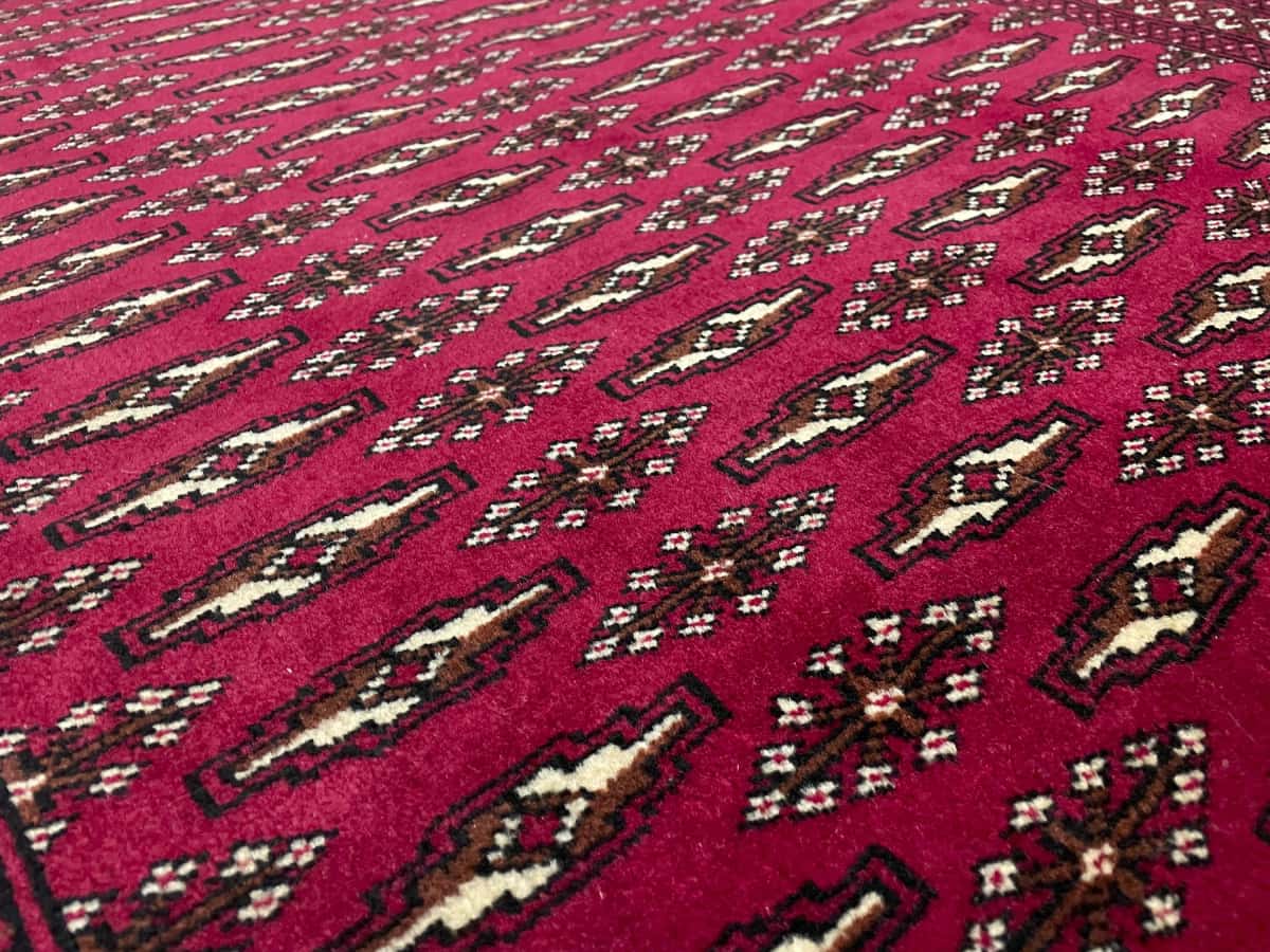 alfombra persa de estilo turcomana en dimensiones 148 centímetros de largo por 101 centímetros de ancho con colores principalmente rojo — Primer plano de la textura