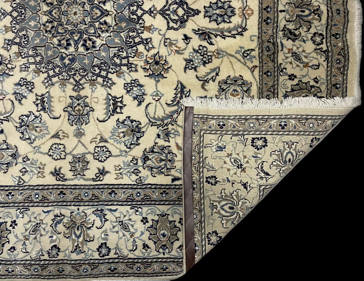 alfombra persa de estilo Nain en dimensiones 212 centímetros de largo por 194 centímetros de ancho con colores principalmente beige y azul — Plegada