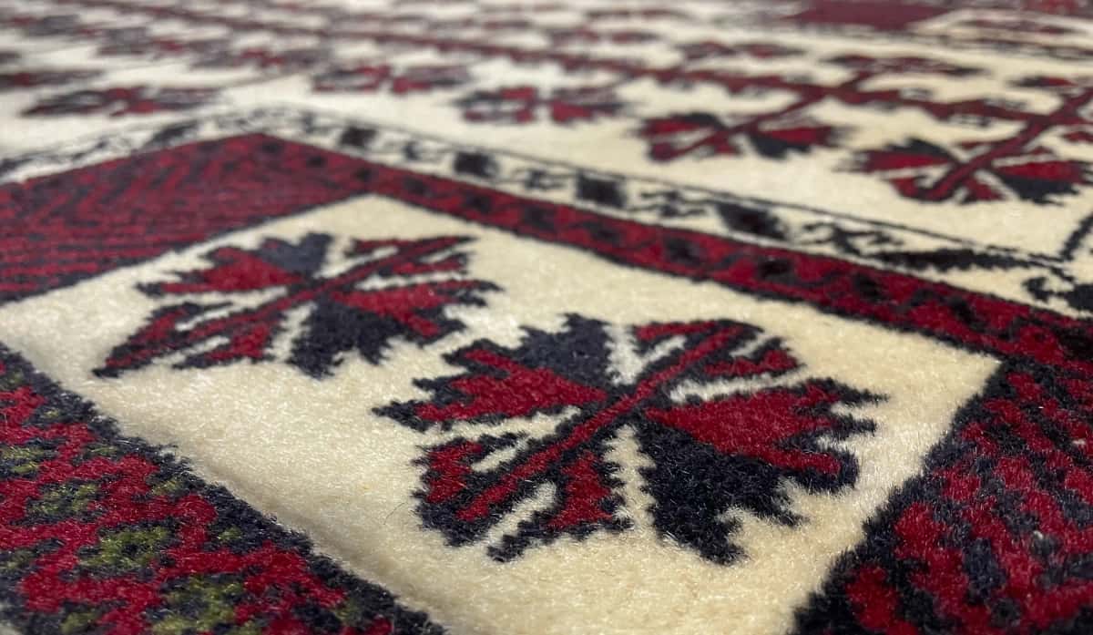 Persian rug of Turkoman style in dimensions 145 centimeters length by 101 centimeters width with mainly beige and red colors — Texture close-up