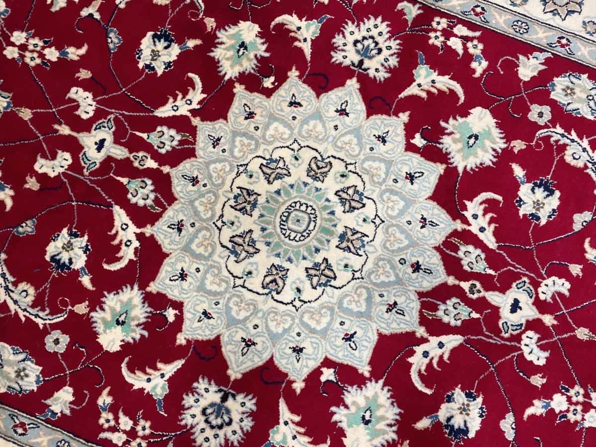 Persian rug of Nain style in dimensions 208 centimeters length by 150 centimeters width with mainly red colors — Texture close-up
