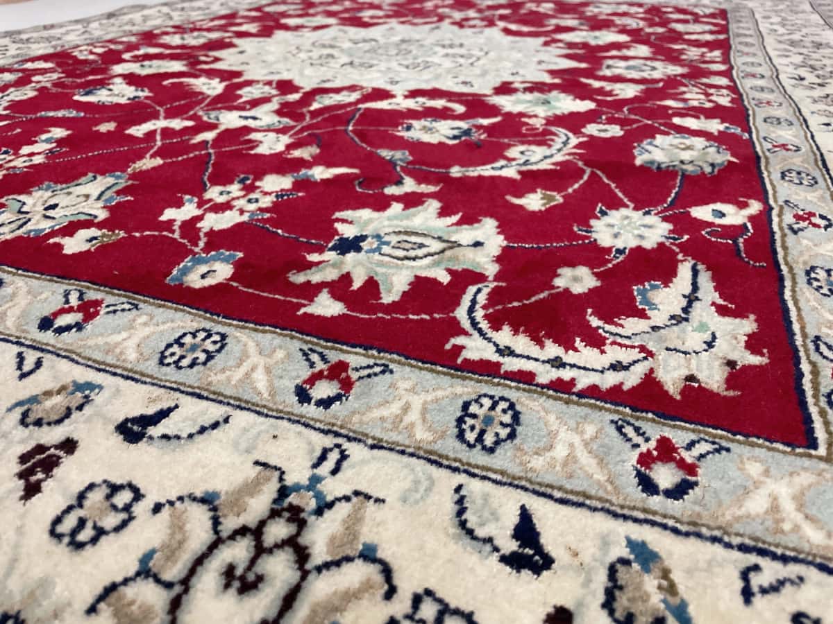 Persian rug of Nain style in dimensions 208 centimeters length by 150 centimeters width with mainly red colors — Texture close-up