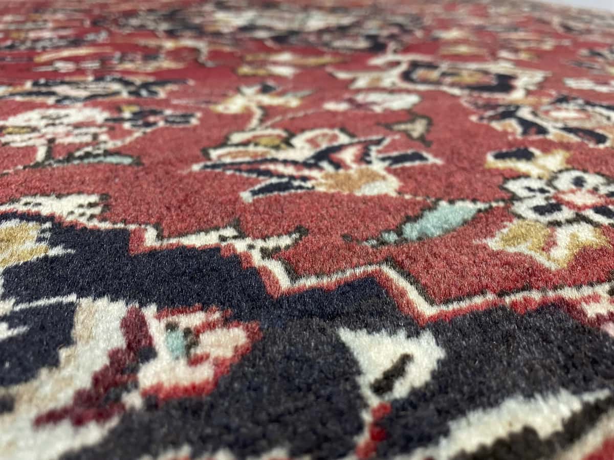 Persian rug of Kashan style in dimensions 143 centimeters length by 111 centimeters width with mainly red colors — Texture close-up