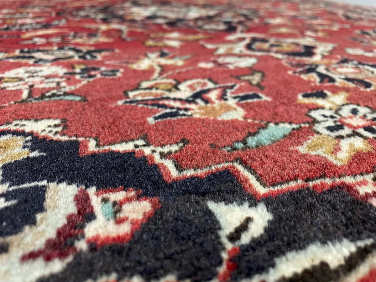 persischer Teppich im Kashan Stil in den Maßen 143 Zentimeter Länge mal 111 Zentimeter Breite mit überwiegend rot Farben — Nahaufnahme der Textur