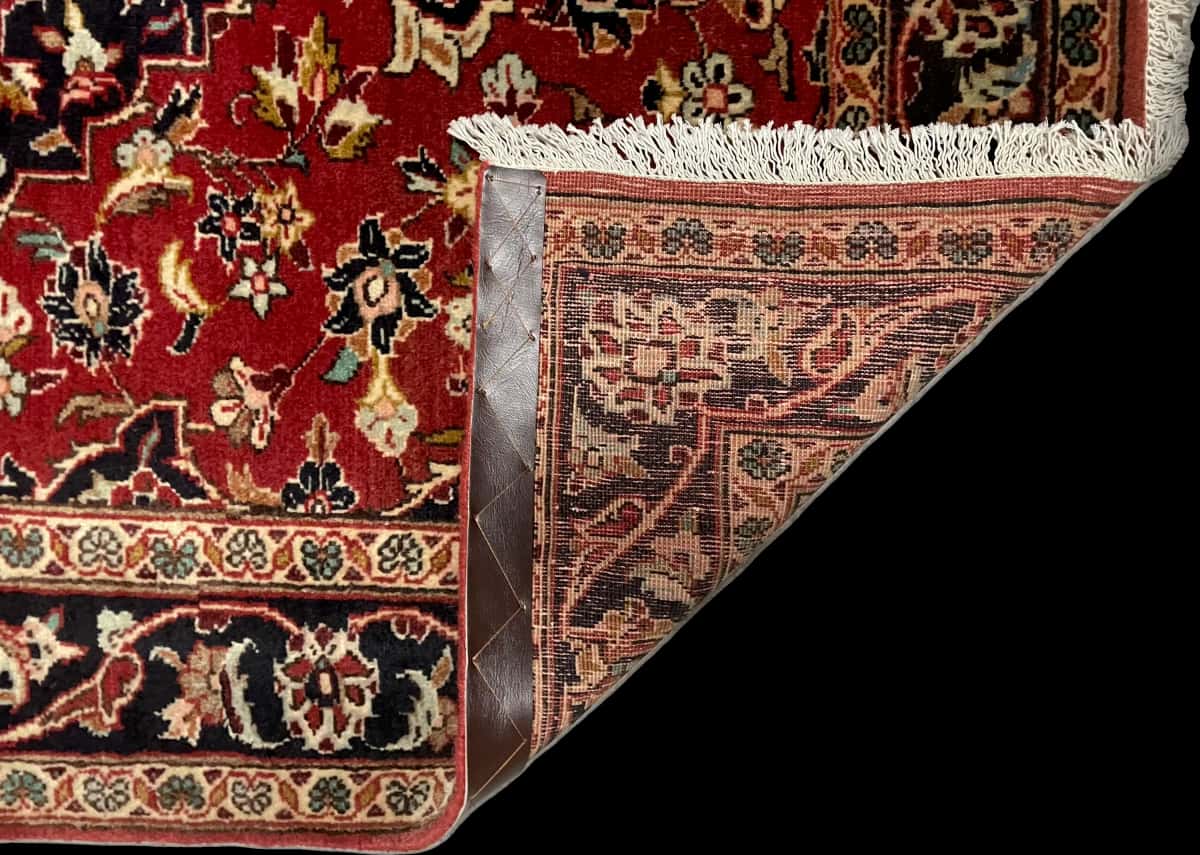 persischer Teppich im Kashan Stil in den Maßen 143 Zentimeter Länge mal 111 Zentimeter Breite mit überwiegend rot Farben — Gefaltet
