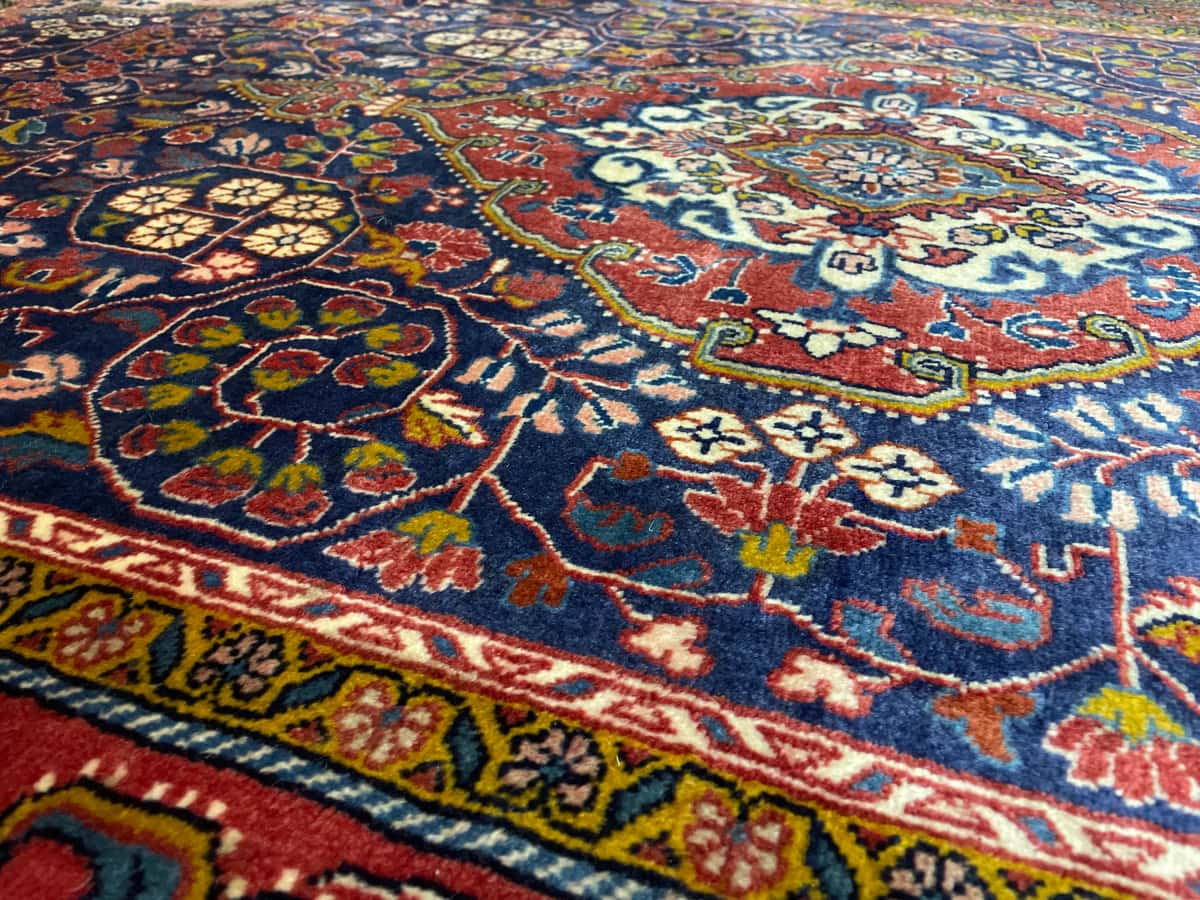 persischer Teppich im Malayer Stil in den Maßen 209 Zentimeter Länge mal 131 Zentimeter Breite mit überwiegend rot und blau Farben — Nahaufnahme der Textur
