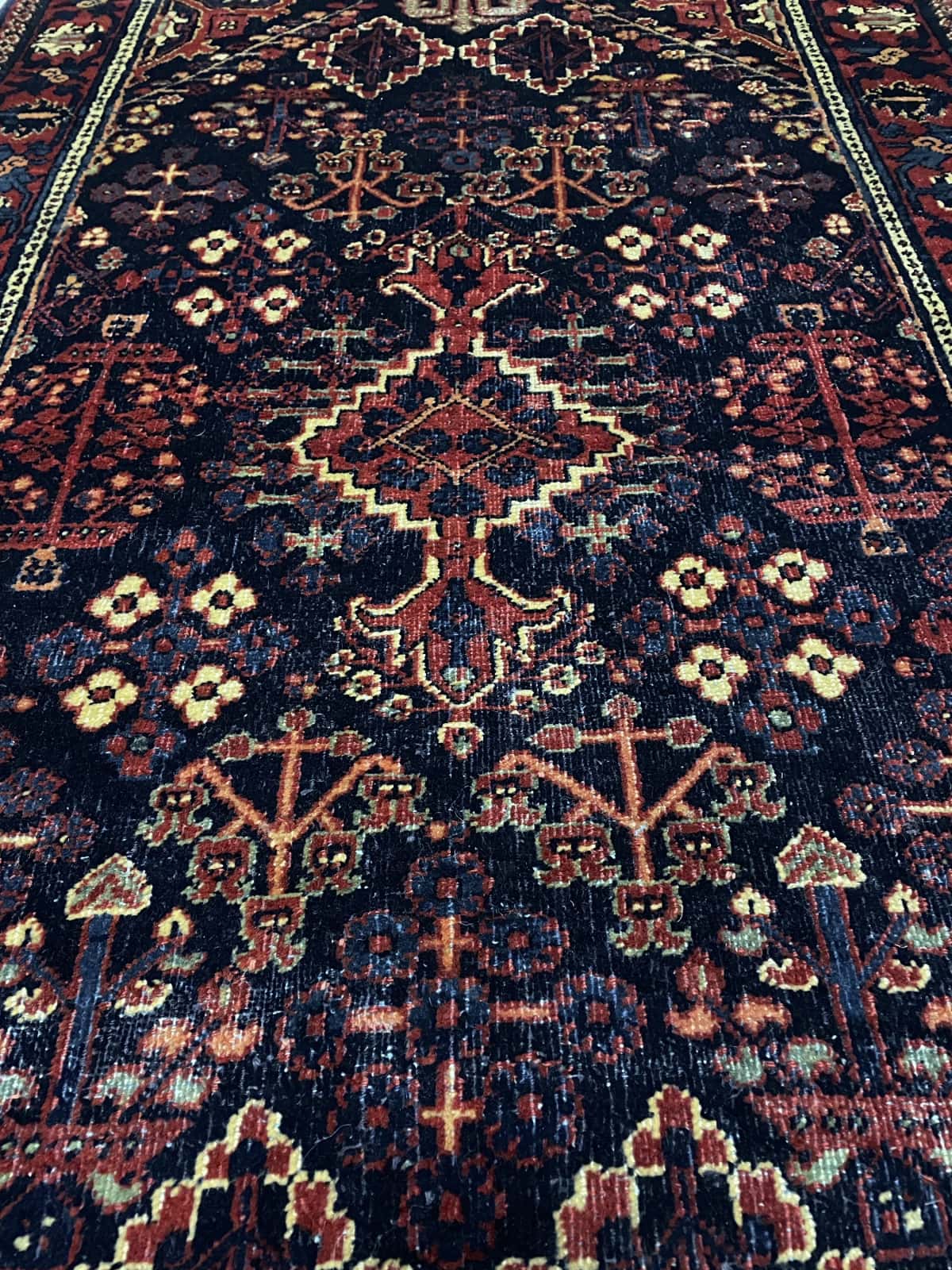 Persian rug of Kerman style in dimensions 157 centimeters length by 100 centimeters width with mainly red and blue colors — Texture close-up