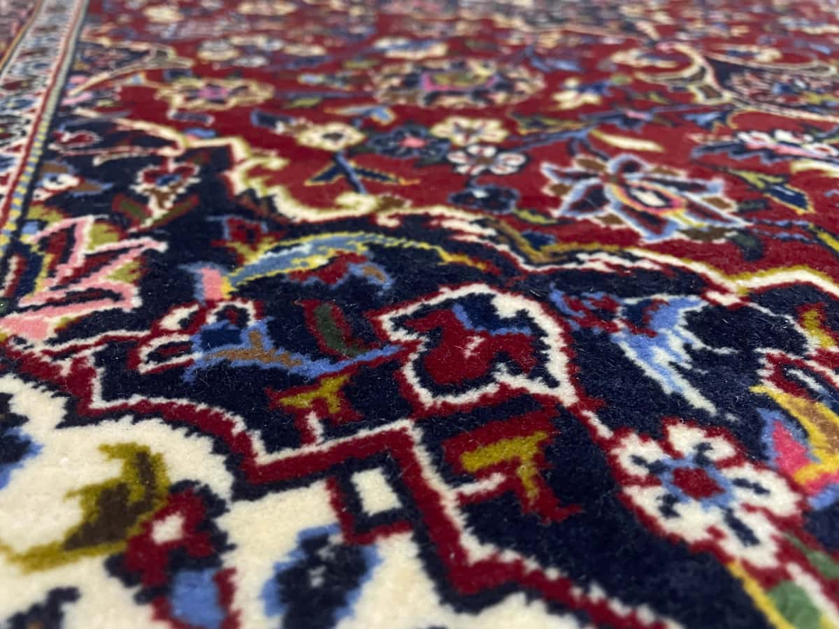 Persian rug of Kashan style in dimensions 164 centimeters length by 105 centimeters width with mainly red and blue colors — Texture close-up