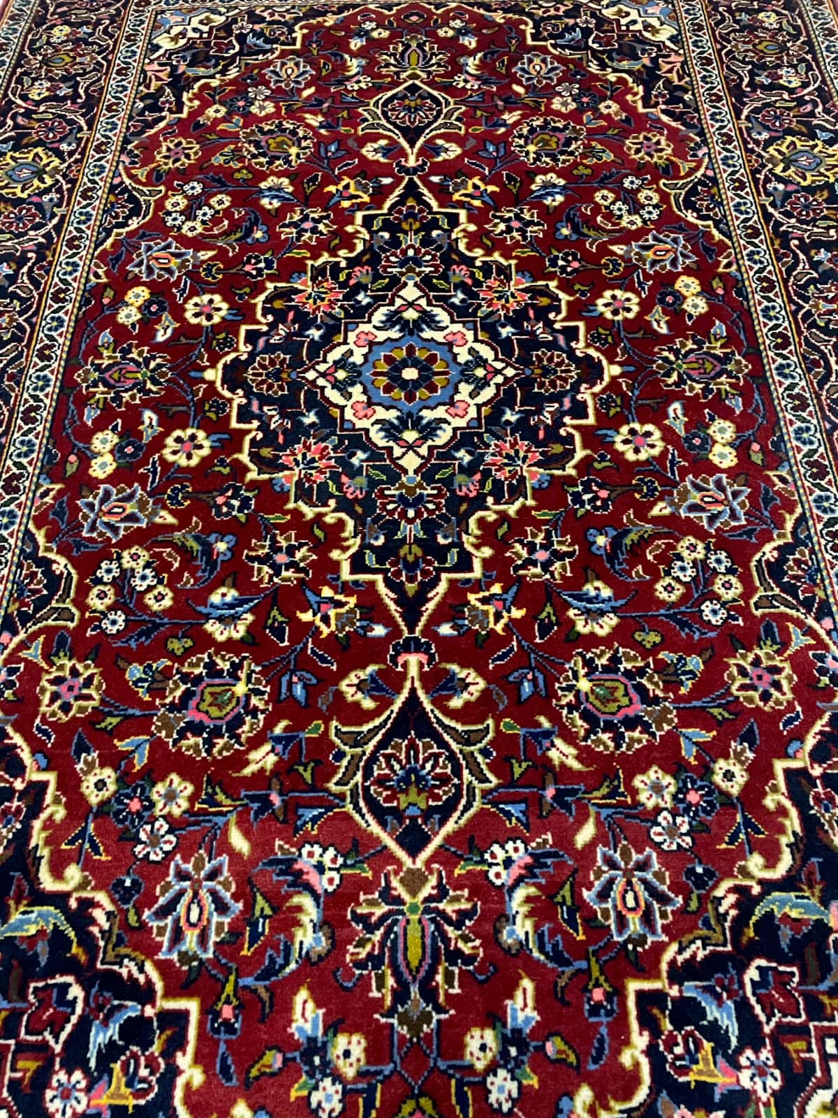 persischer Teppich im Kashan Stil in den Maßen 164 Zentimeter Länge mal 105 Zentimeter Breite mit überwiegend rot Farben — Perspektive