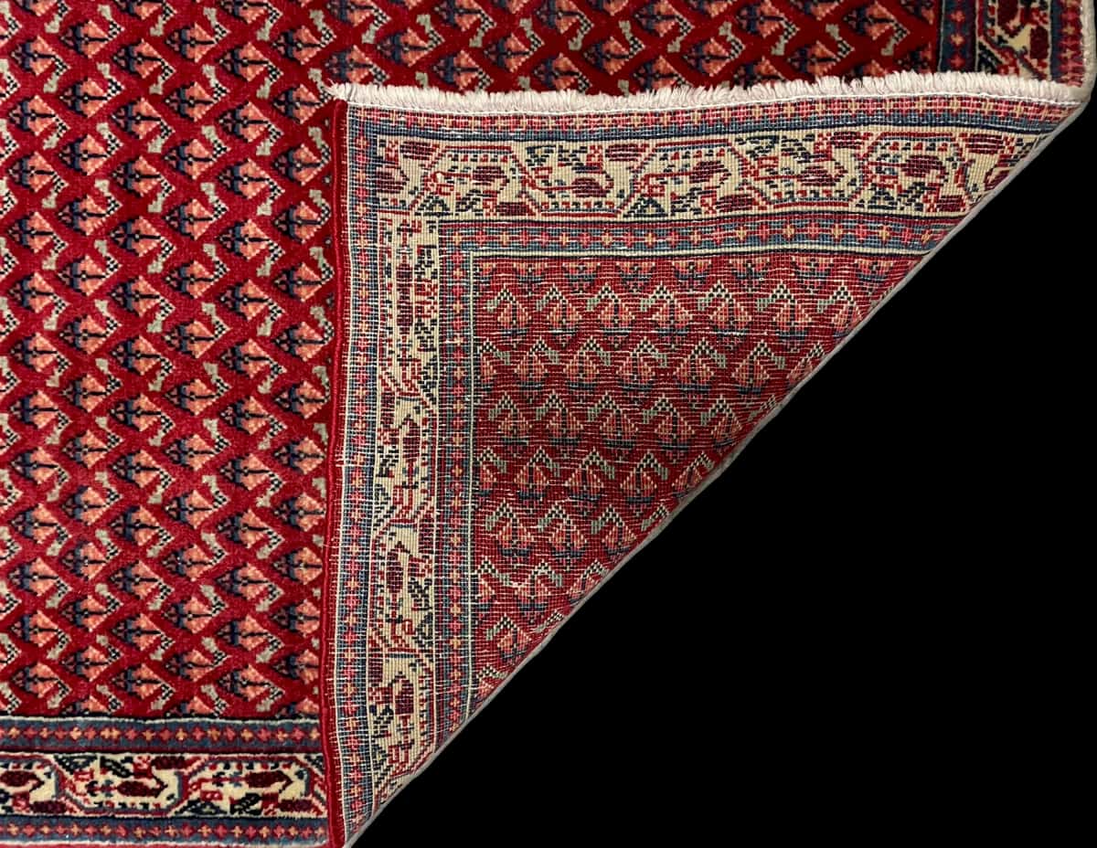 persischer Teppich im Arak Stil in den Maßen 115 Zentimeter Länge mal 67 Zentimeter Breite mit überwiegend rot und blau Farben — Gefaltet