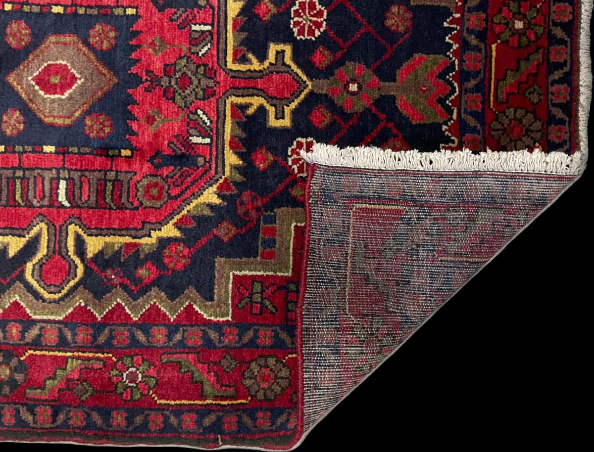 alfombra persa de estilo Nahavand en dimensiones 155 centímetros de largo por 115 centímetros de ancho con colores principalmente rojo — Plegada