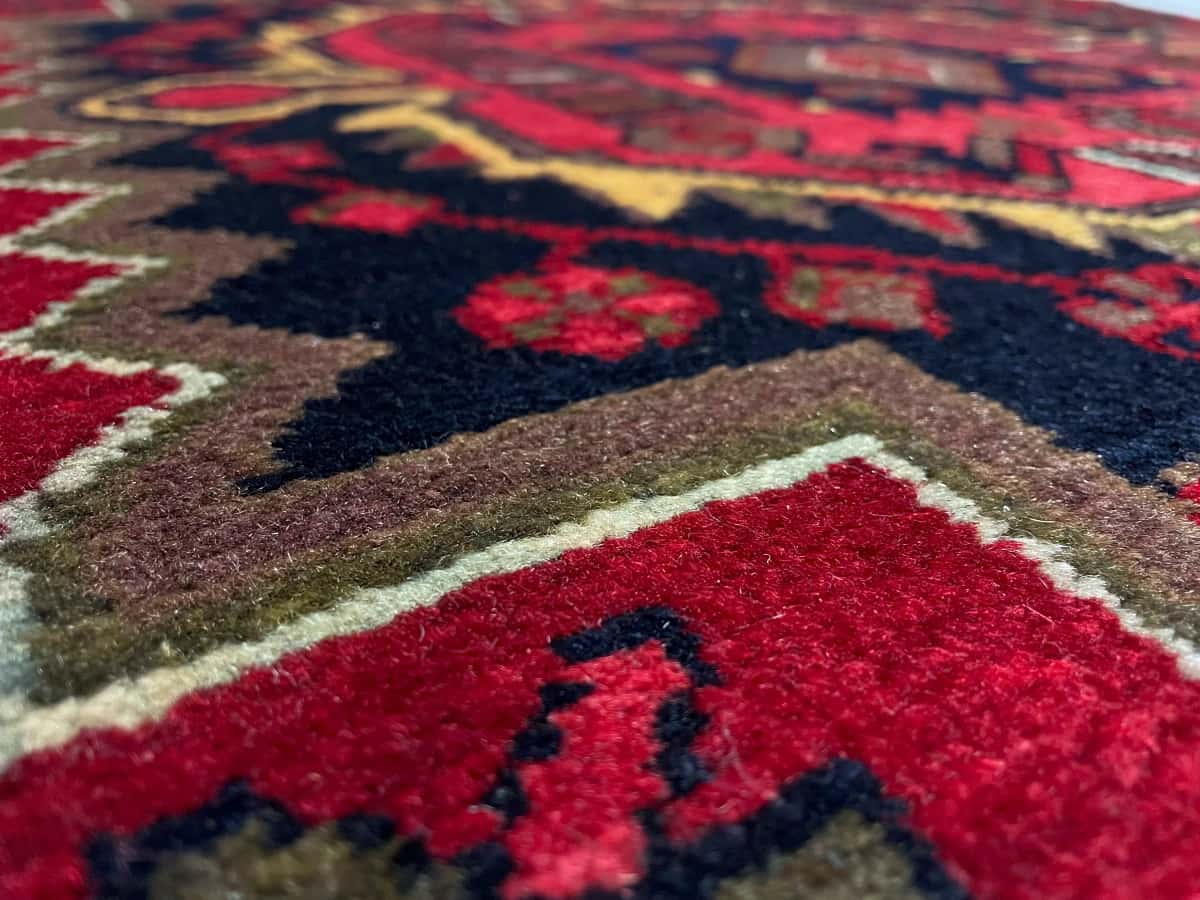 persischer Teppich im Nahavand Stil in den Maßen 155 Zentimeter Länge mal 115 Zentimeter Breite mit überwiegend rot Farben — Nahaufnahme der Textur