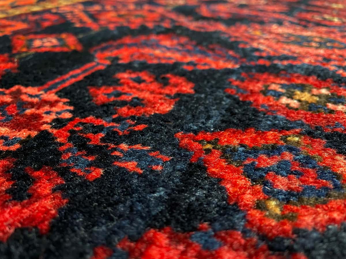 persischer Teppich im turkmenischer Stil in den Maßen 164 Zentimeter Länge mal 106 Zentimeter Breite mit überwiegend rot und blau Farben — Nahaufnahme der Textur