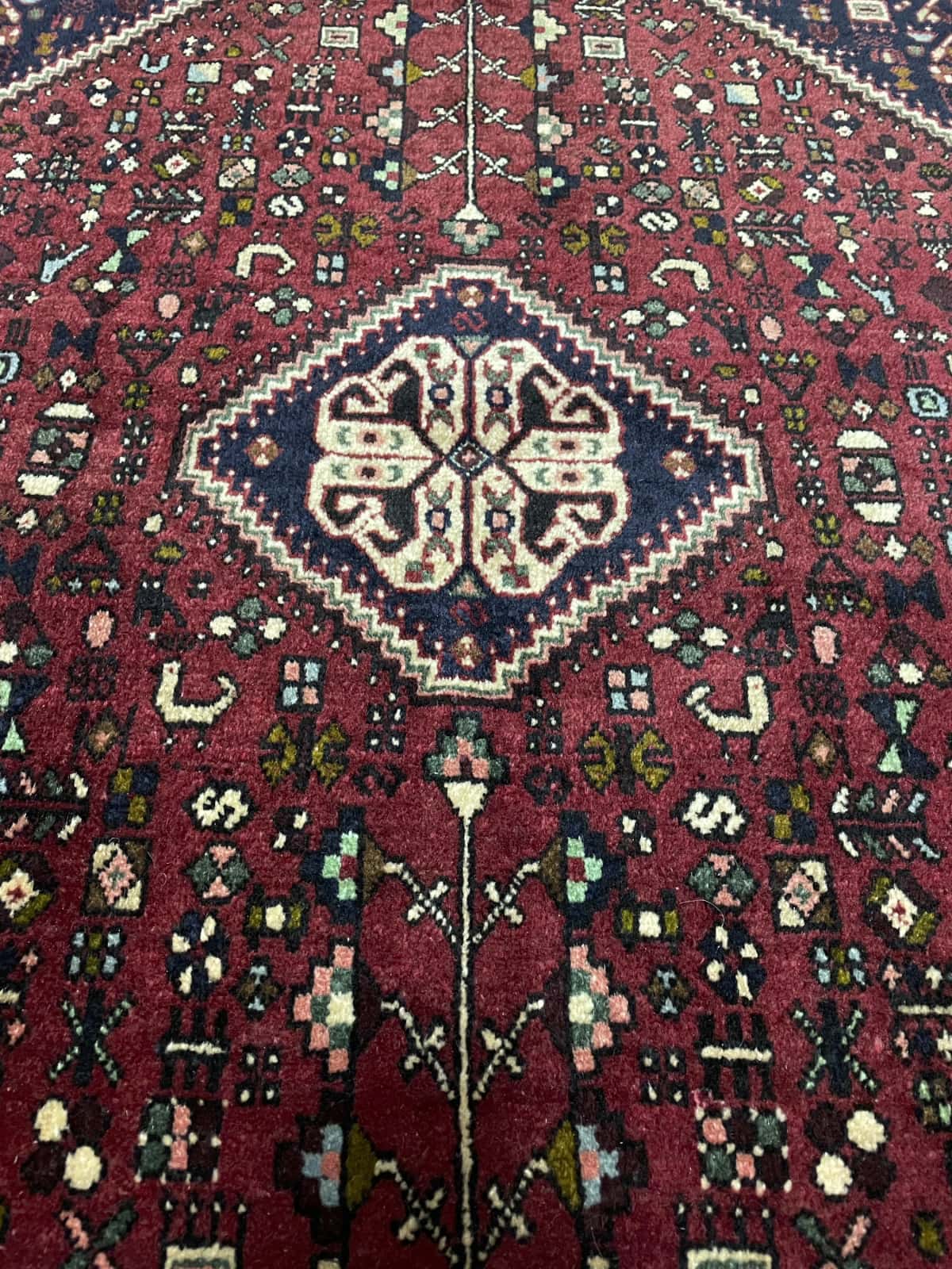 Persian rug of Abadeh style in dimensions 152 centimeters length by 109 centimeters width with mainly red colors — Texture close-up