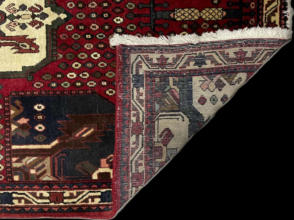 alfombra persa de estilo Shahr-e Babak en dimensiones 162 centímetros de largo por 107 centímetros de ancho con colores principalmente rojo — Plegada