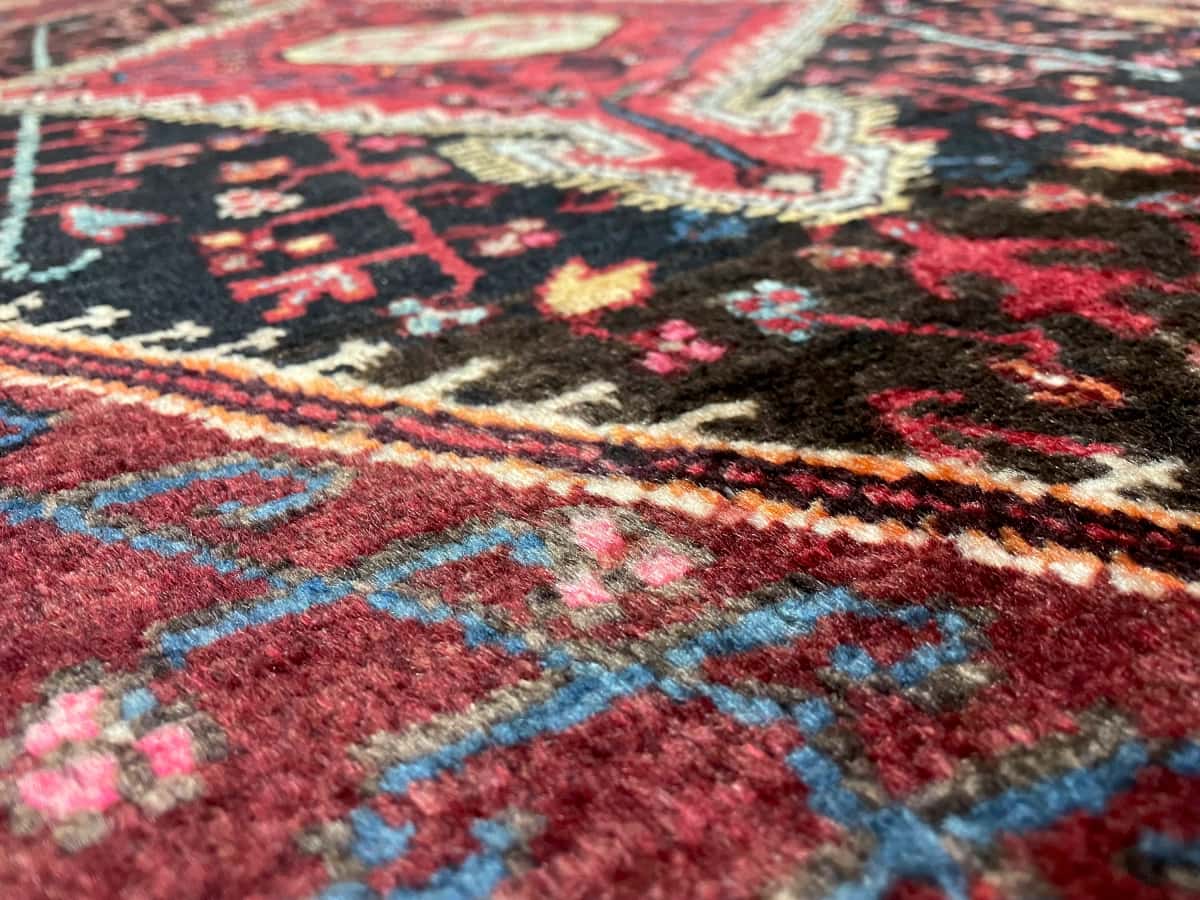 persischer Teppich im Sirjan Stil in den Maßen 160 Zentimeter Länge mal 113 Zentimeter Breite mit überwiegend rot Farben — Nahaufnahme der Textur