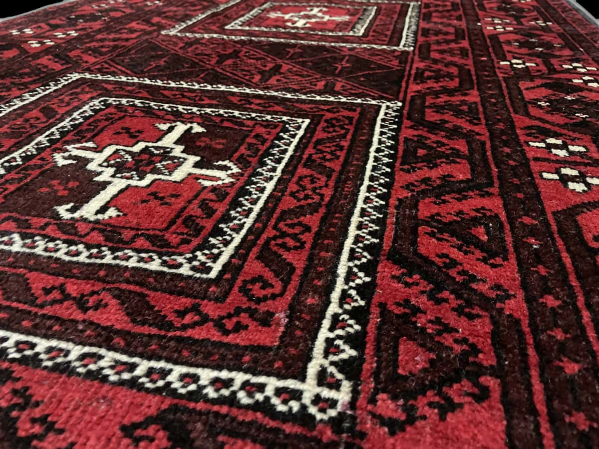 Persian rug of Baluch style in dimensions 208 centimeters length by 107 centimeters width with mainly red colors — Texture close-up
