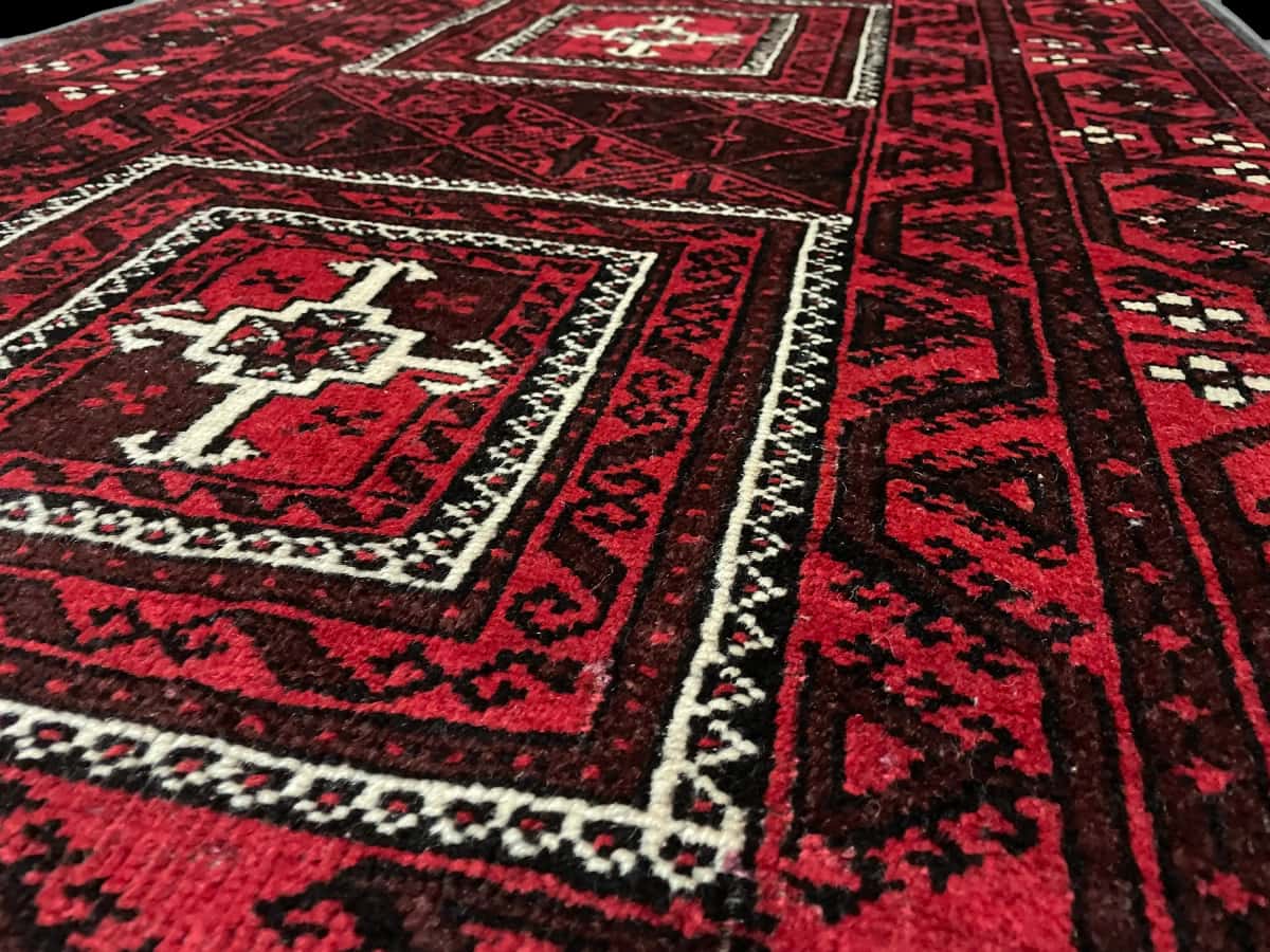persischer Teppich im Baluch Stil in den Maßen 208 Zentimeter Länge mal 107 Zentimeter Breite mit überwiegend rot Farben — Nahaufnahme der Textur