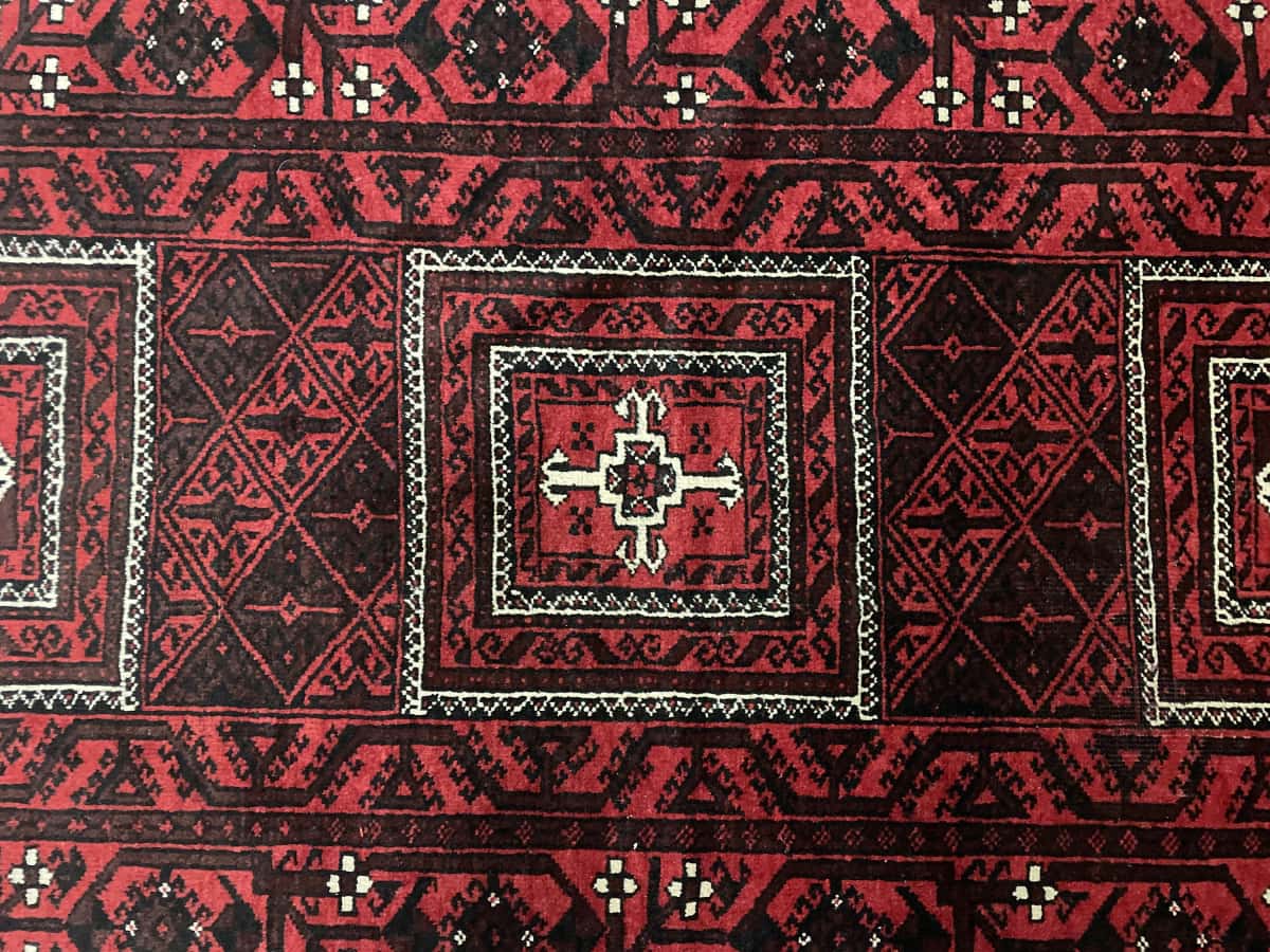 Persian rug of Baluch style in dimensions 208 centimeters length by 107 centimeters width with mainly red colors — Texture close-up