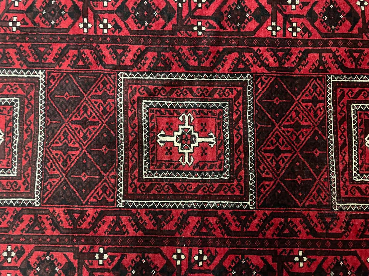 persischer Teppich im Baluch Stil in den Maßen 208 Zentimeter Länge mal 107 Zentimeter Breite mit überwiegend rot Farben — Nahaufnahme der Textur