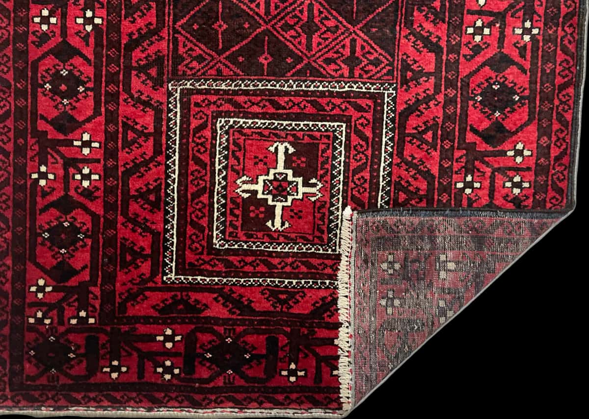 persischer Teppich im Baluch Stil in den Maßen 208 Zentimeter Länge mal 107 Zentimeter Breite mit überwiegend rot Farben — Gefaltet
