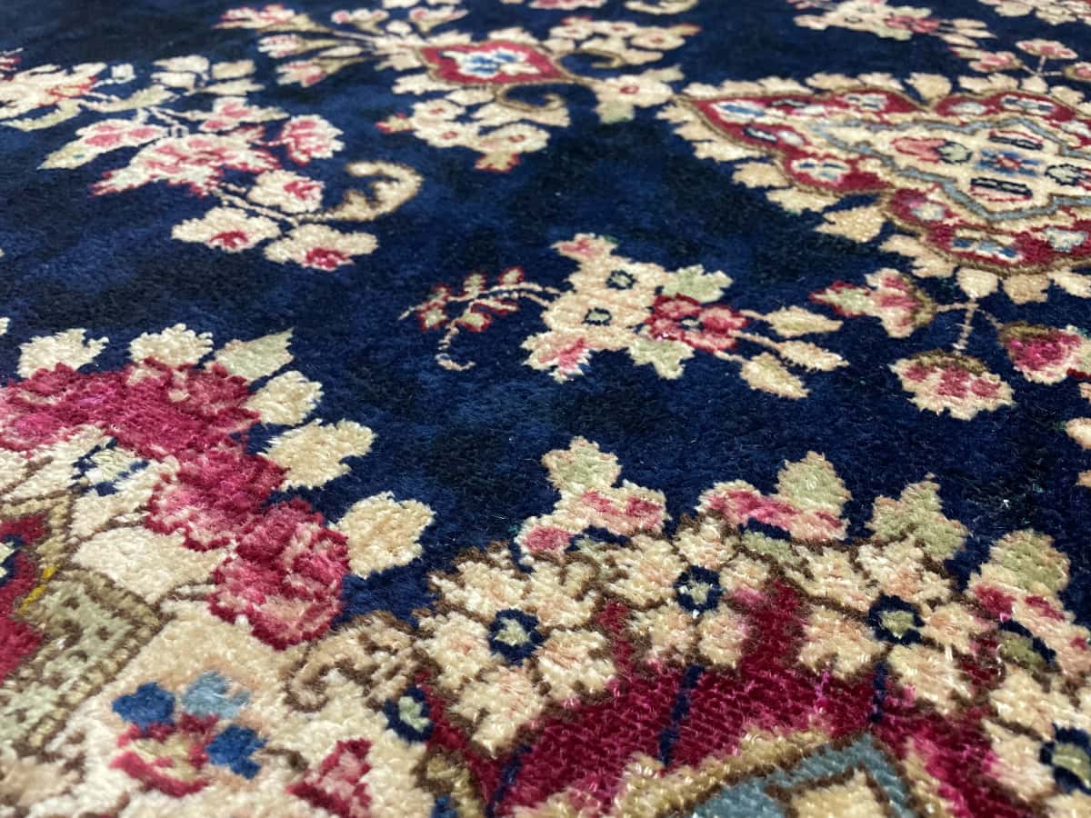 Persian rug of Kerman style in dimensions 217 centimeters length by 123 centimeters width with mainly red and blue colors — Texture close-up