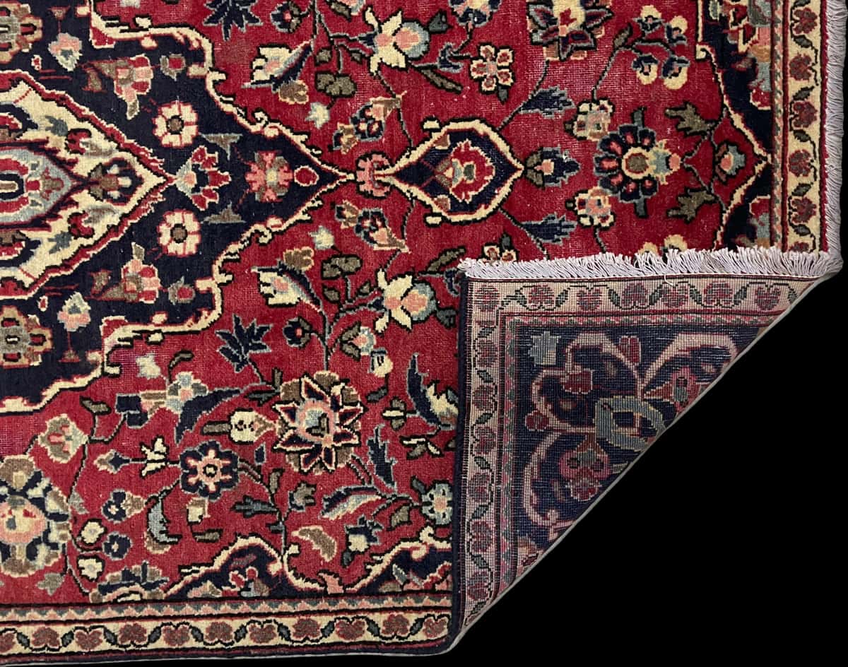 alfombra persa de estilo Aran va Bidgol en dimensiones 160 centímetros de largo por 100 centímetros de ancho con colores principalmente rojo — Plegada