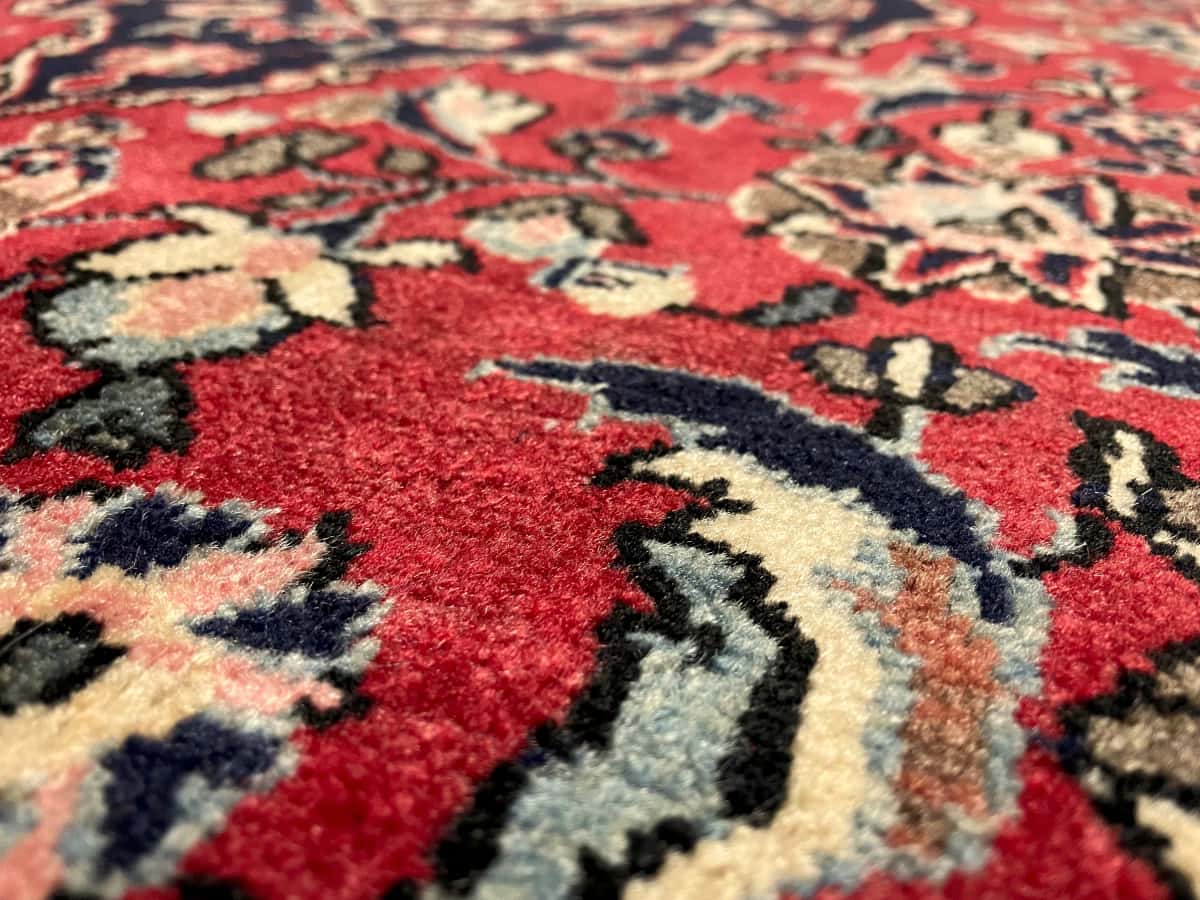 persischer Teppich im Aran va Bidgol Stil in den Maßen 160 Zentimeter Länge mal 100 Zentimeter Breite mit überwiegend rot Farben — Nahaufnahme der Textur