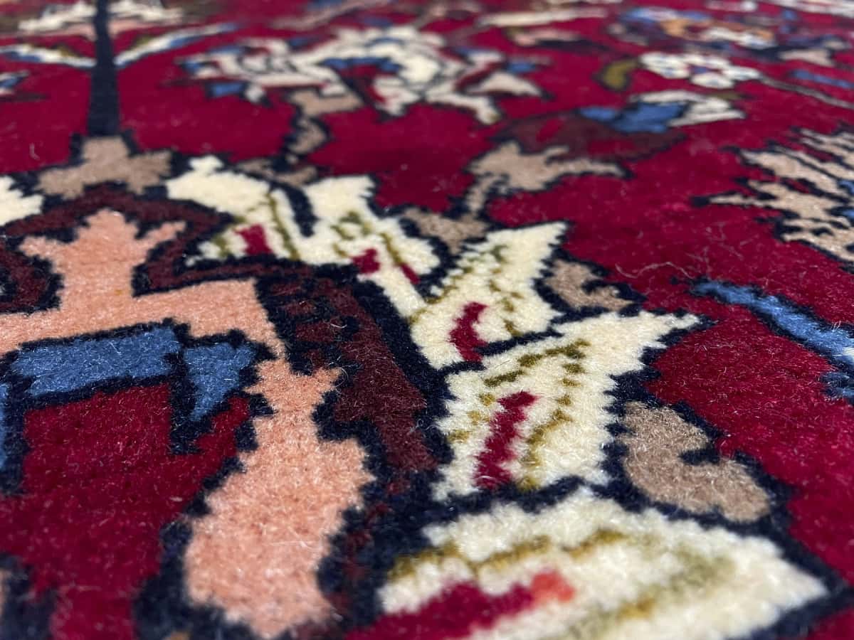 alfombra persa de estilo baluch en dimensiones 220 centímetros de largo por 137 centímetros de ancho con colores principalmente rojo y azul — Primer plano de la textura