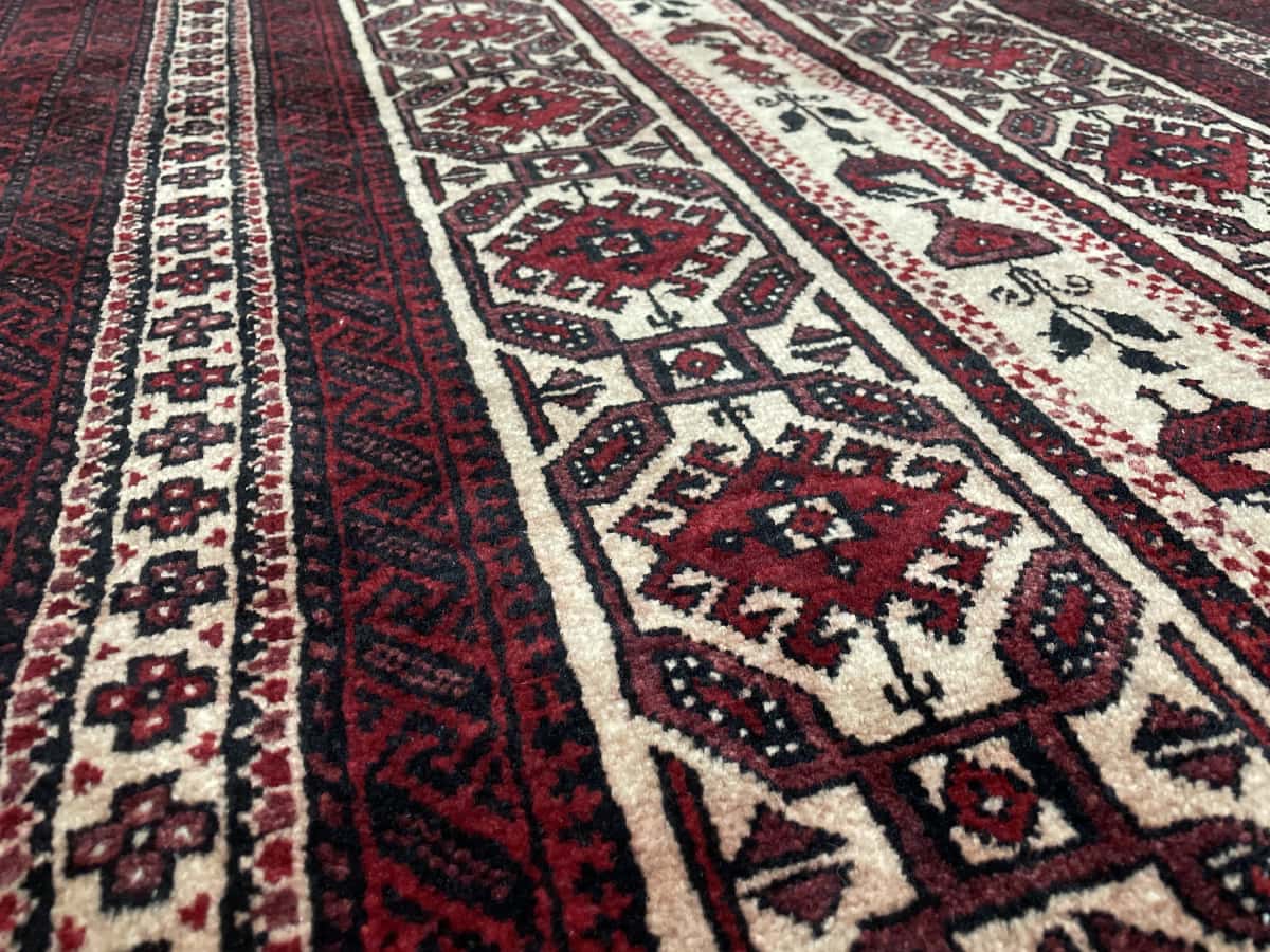 Persian rug of Baluch style in dimensions 205 centimeters length by 108 centimeters width with mainly red colors — Texture close-up