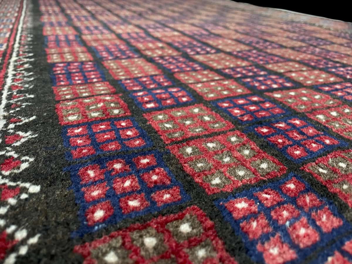 alfombra persa de estilo baluch en dimensiones 170 centímetros de largo por 93 centímetros de ancho con colores principalmente marrón y azul — Primer plano de la textura