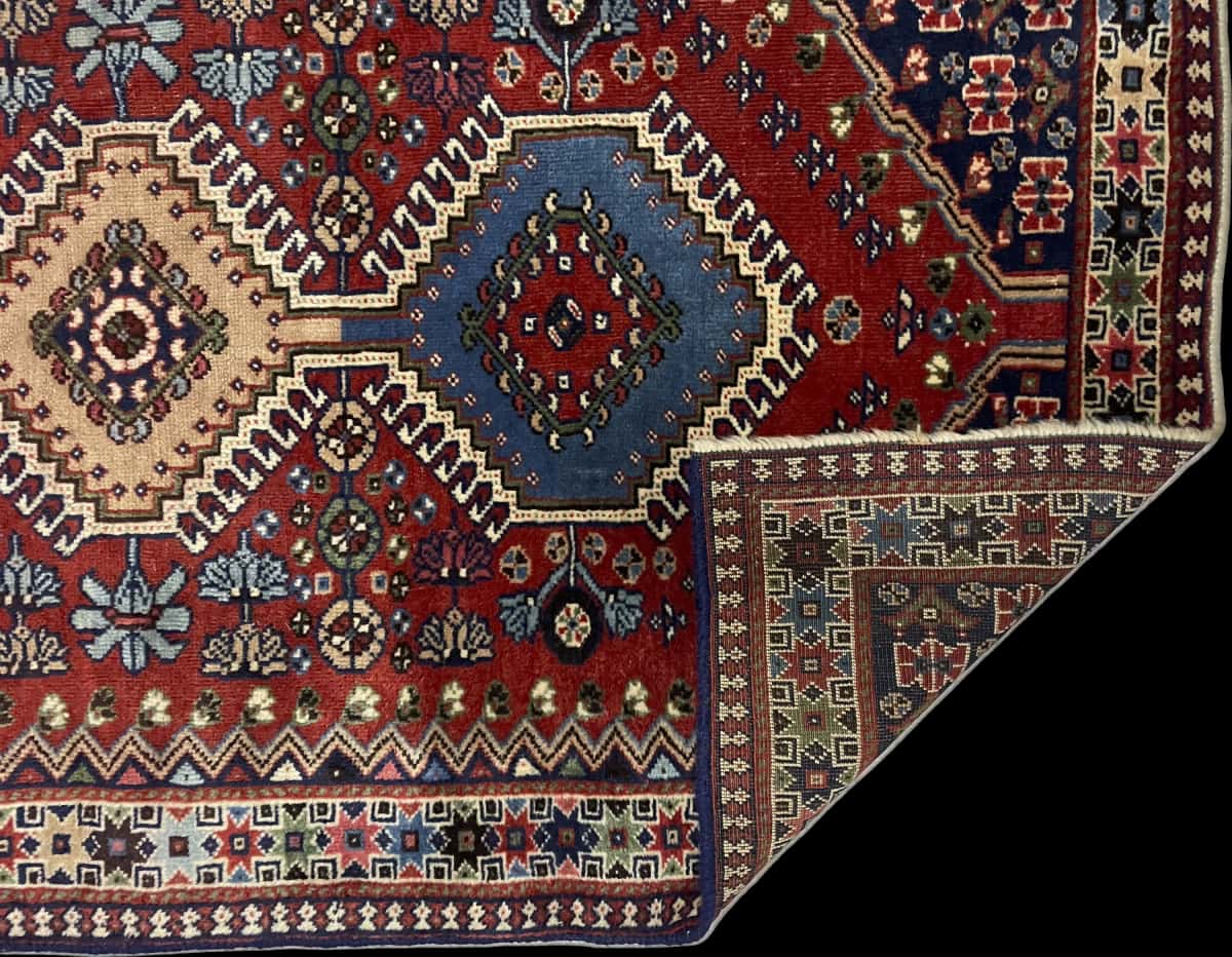 alfombra persa de estilo bakhtiari en dimensiones 148 centímetros de largo por 85 centímetros de ancho con colores principalmente azul y naranja — Plegada