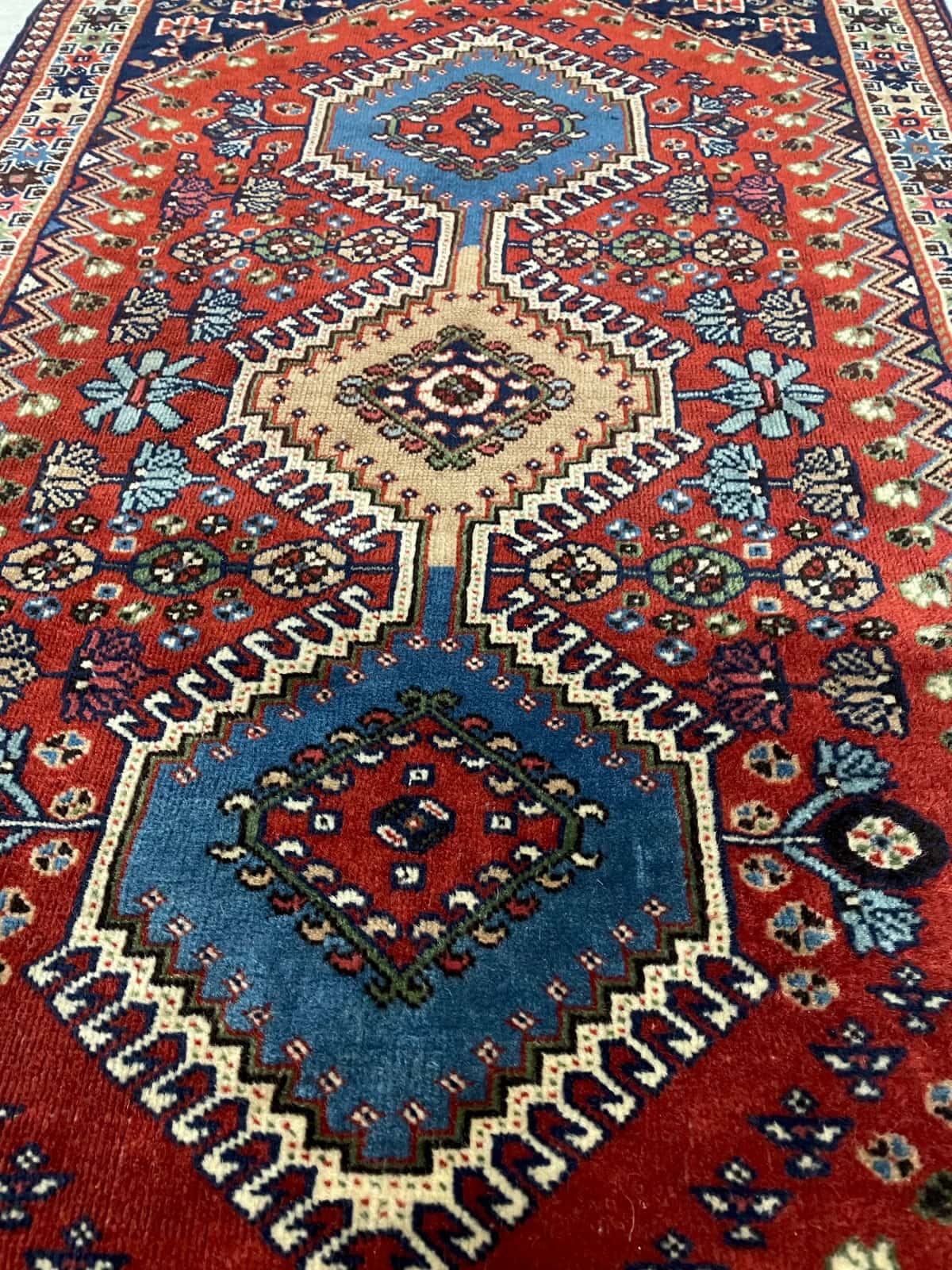 persischer Teppich im Bakhtiari Stil in den Maßen 148 Zentimeter Länge mal 85 Zentimeter Breite mit überwiegend blau und orange Farben — Perspektive