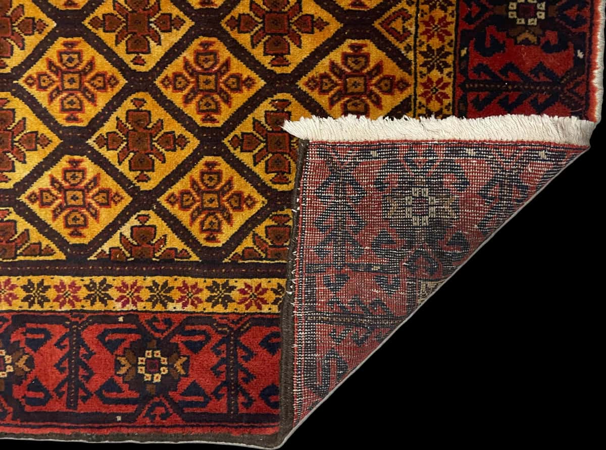 alfombra persa de estilo baluch en dimensiones 176 centímetros de largo por 91 centímetros de ancho con colores principalmente naranja y amarillo — Plegada